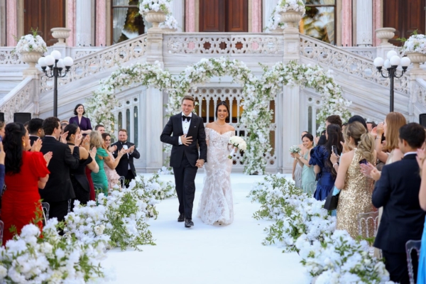 A couple exit their wedding ceremony at Cirigan Palace Kempinski, Istanbul, led by luxury wedding officiant Nat Raybould