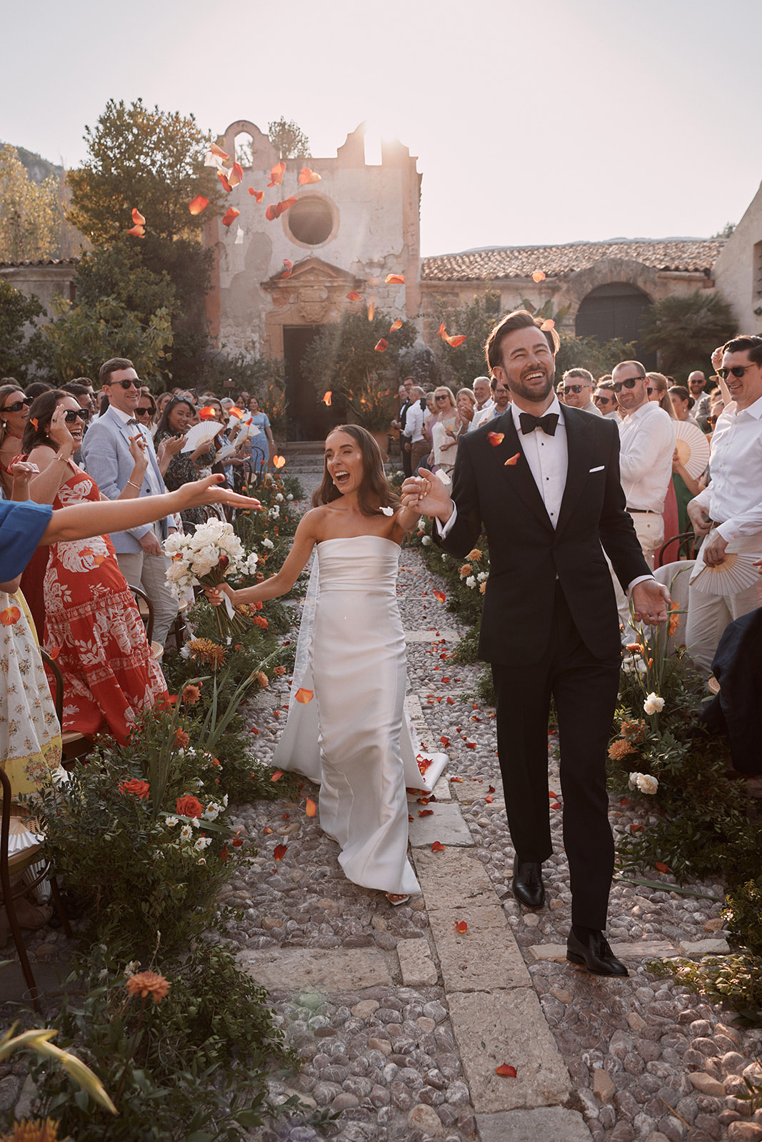 Bride and groom with rose petal confetti at their wedding in Italy. Wiskow and White Italian wedding planners.