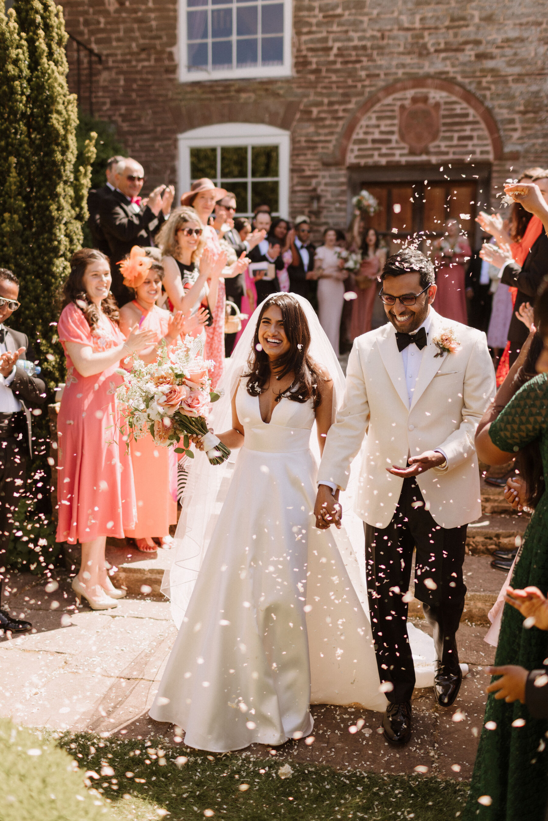 Bride and groom with confetti at Dewsall Court, country house wedding venue in Herefordshire