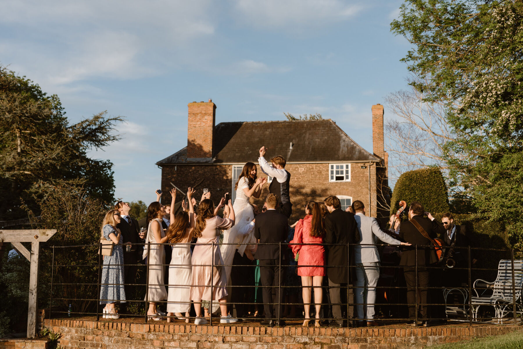 Bride and groom are raised in the air by their wedding guests at Dewsall Court, country house wedding venue in Herefordshire