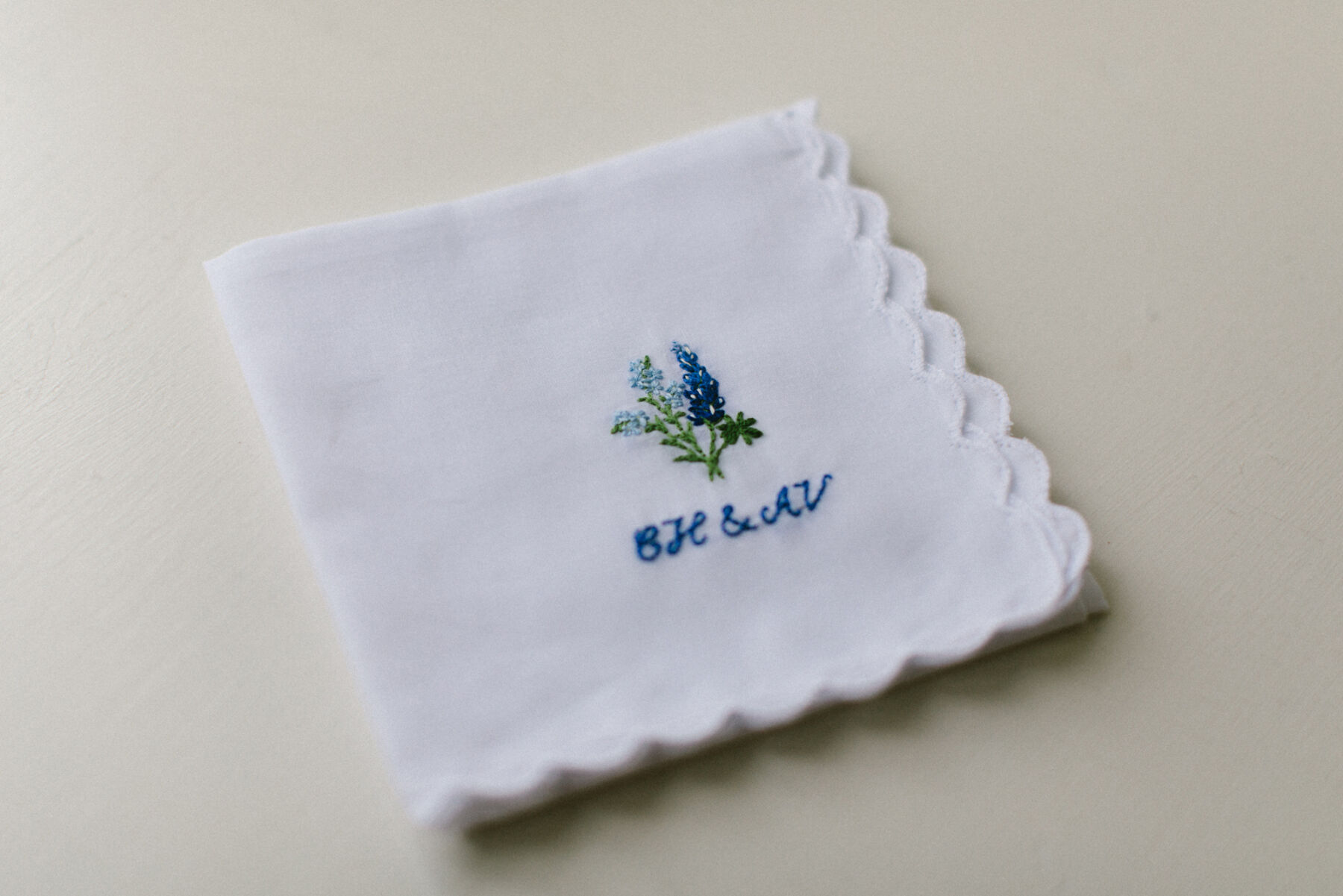 Traditional handkerchief embroidered with the bride and groom's initials and blue flowers native to the bride and groom's place of birth.