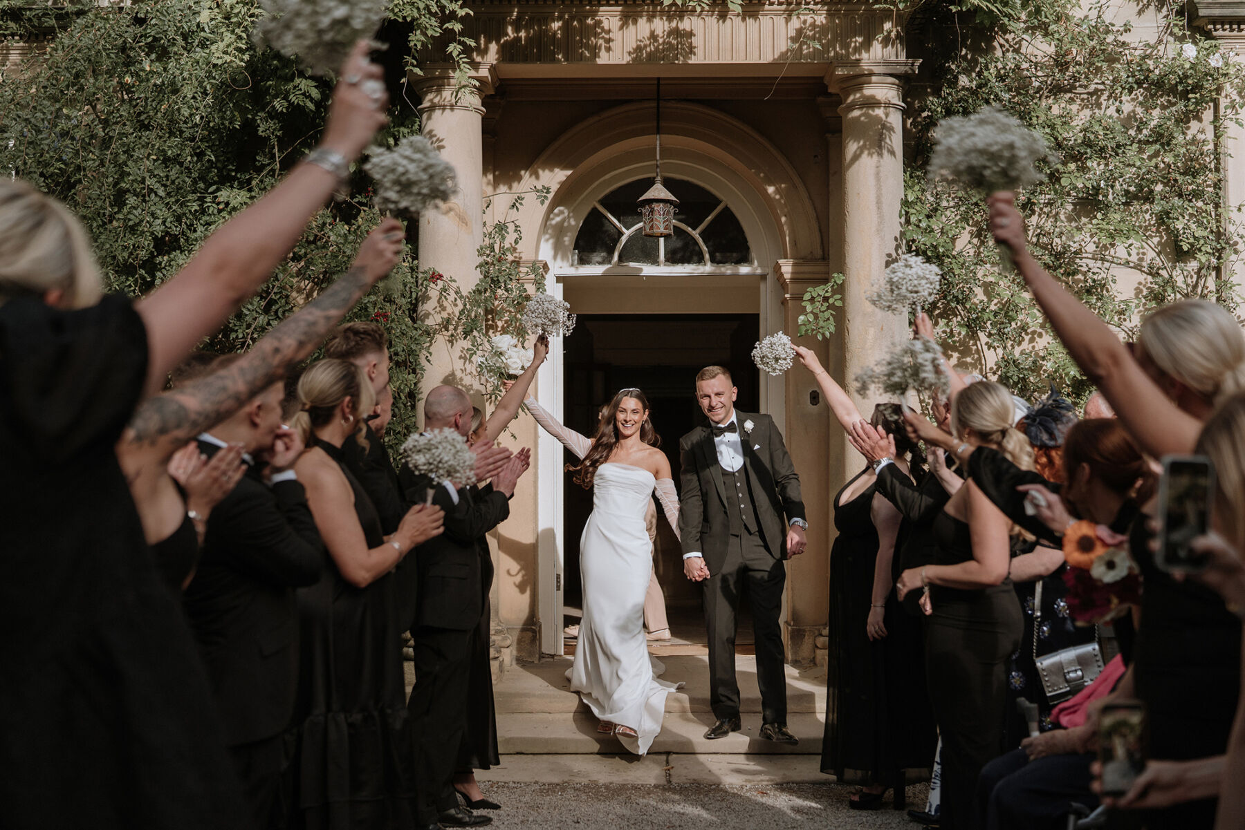 Bride and groom just marred at Middleton Lodge - bridesmaids raising their gypsophila bouquets to celebrate