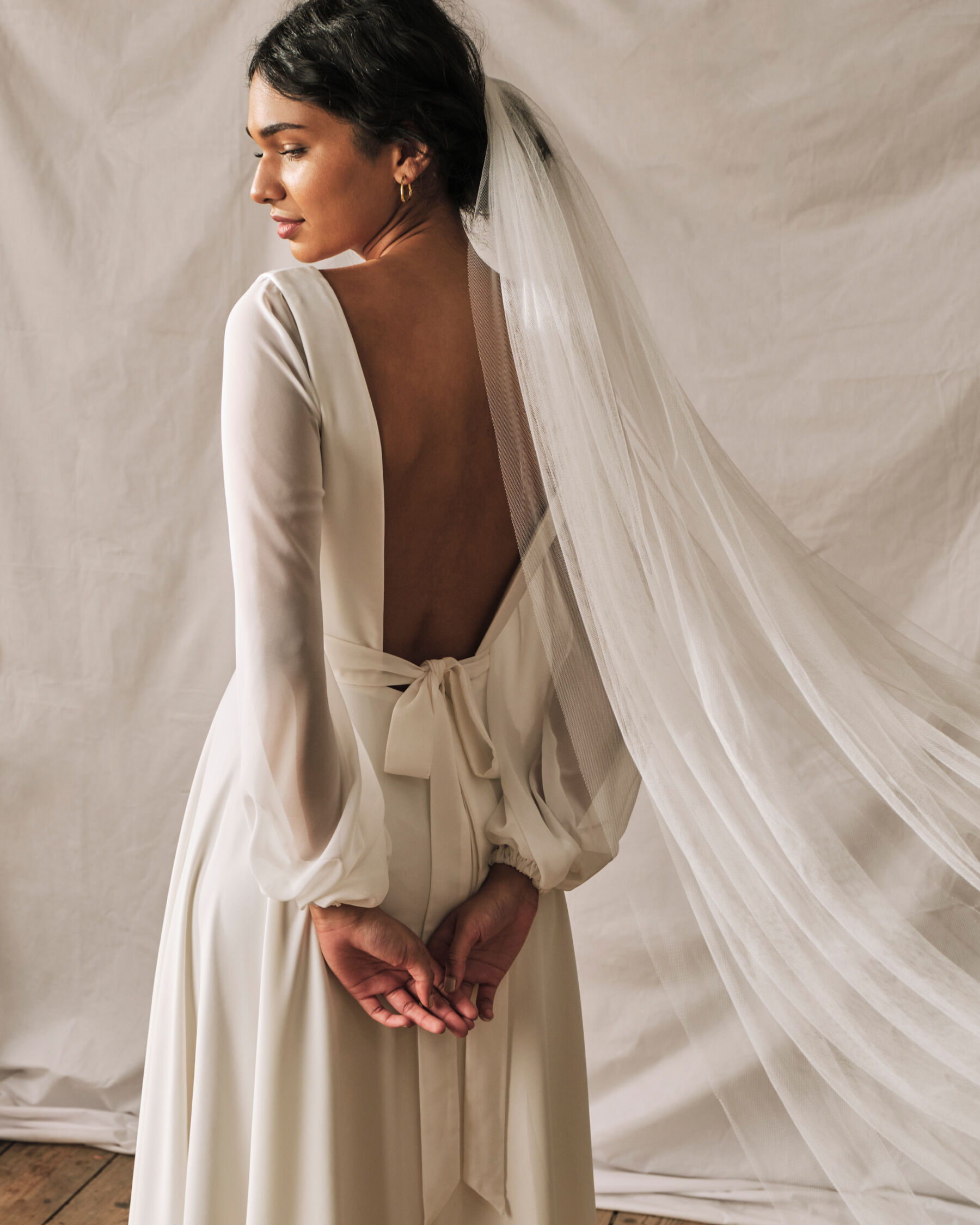 Modern, backless, simple wedding dress by Sophie Rose Bridal. Worn with a long wedding veil.