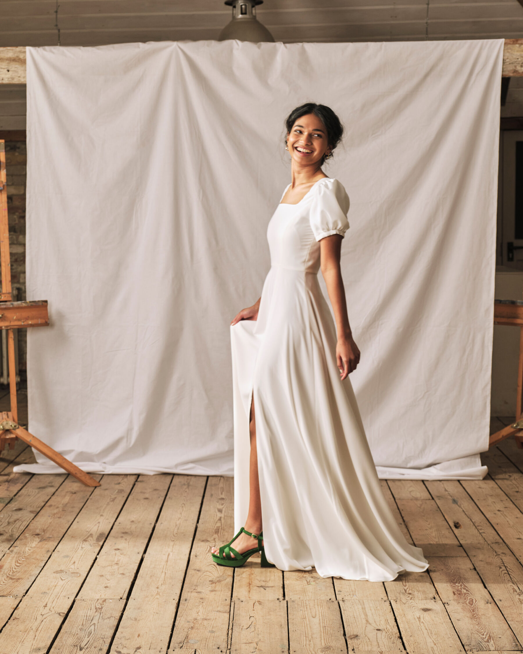 Elegant and simple wedding dress with subtle split from the knee and subtle puff sleeve, worn with green block heel wedding shoes. Dress by Sophie Rose Bridal.