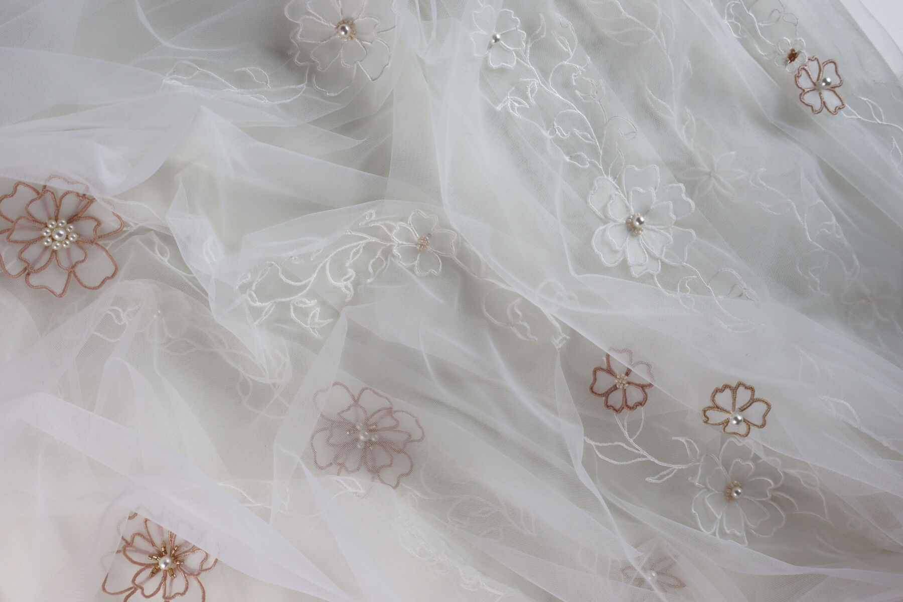 Detail Image of an ivory wedding veil by Natasha Nicole Studio, featuring an array of hand designed embroidered flowers with beaded centres and pearls.