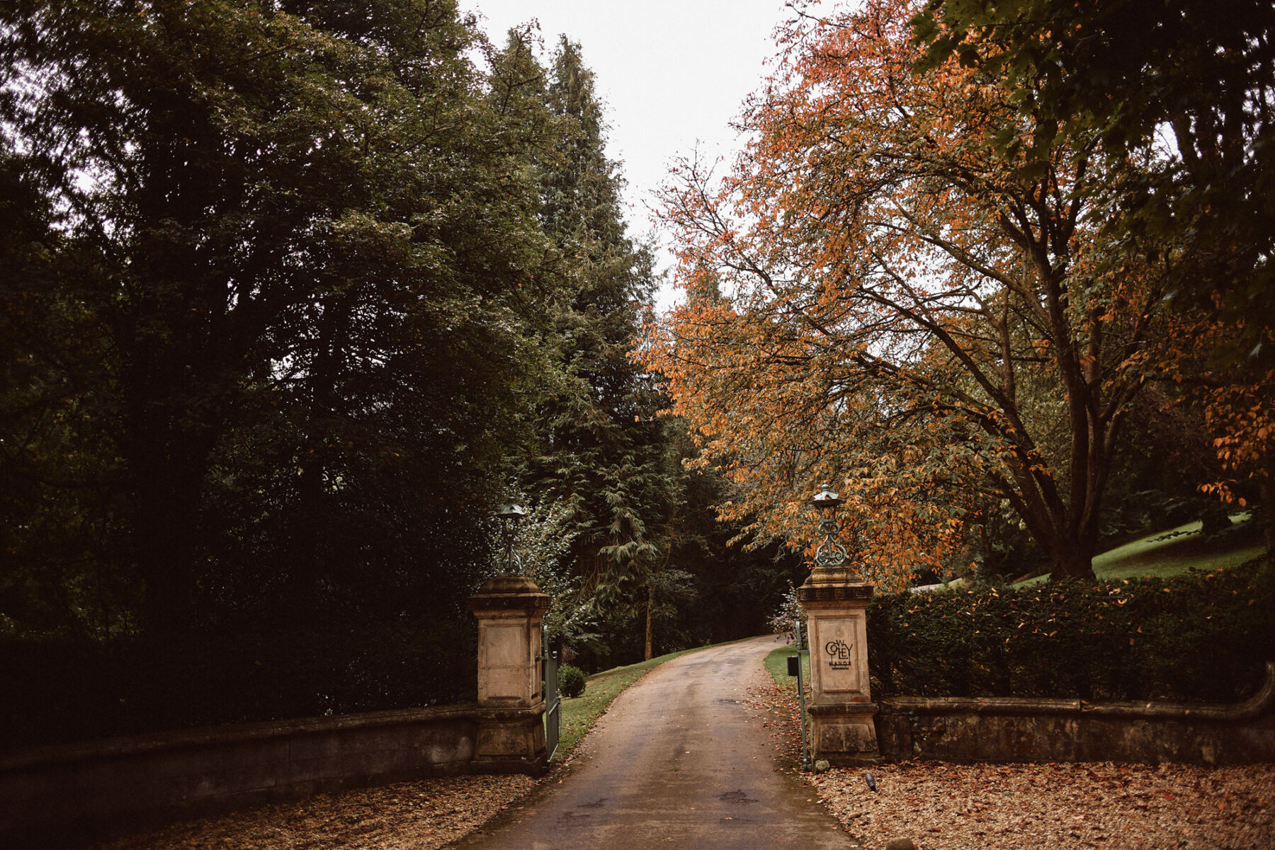 Entrance to Cowley Manor wedding venue in The Cotswolds. September wedding so Autumn leaves falling to the ground.