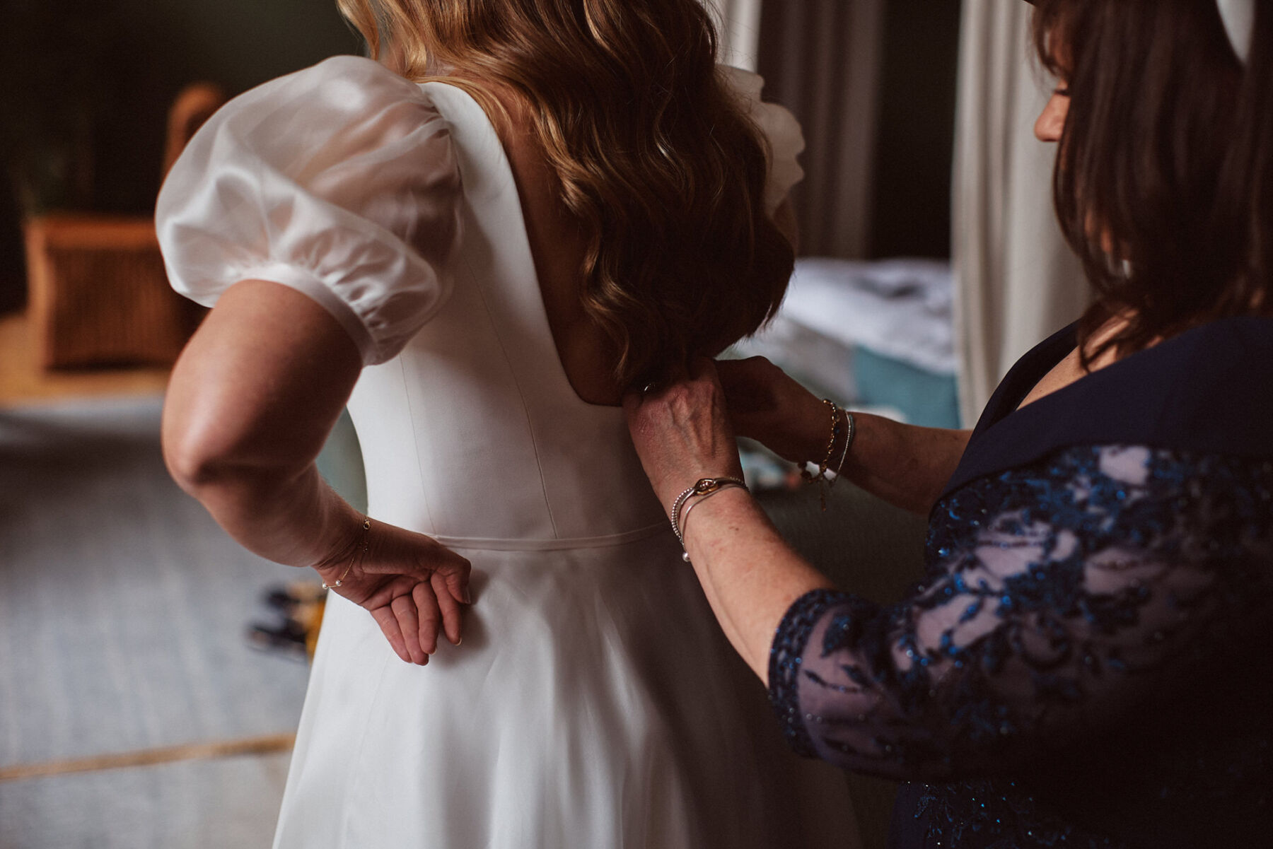 A Romantic, Bridgerton Inspired Wedding at Cowley Manor 14 Mother of the bride buttoning her daughter into her Suzanne Neville wedding dress.