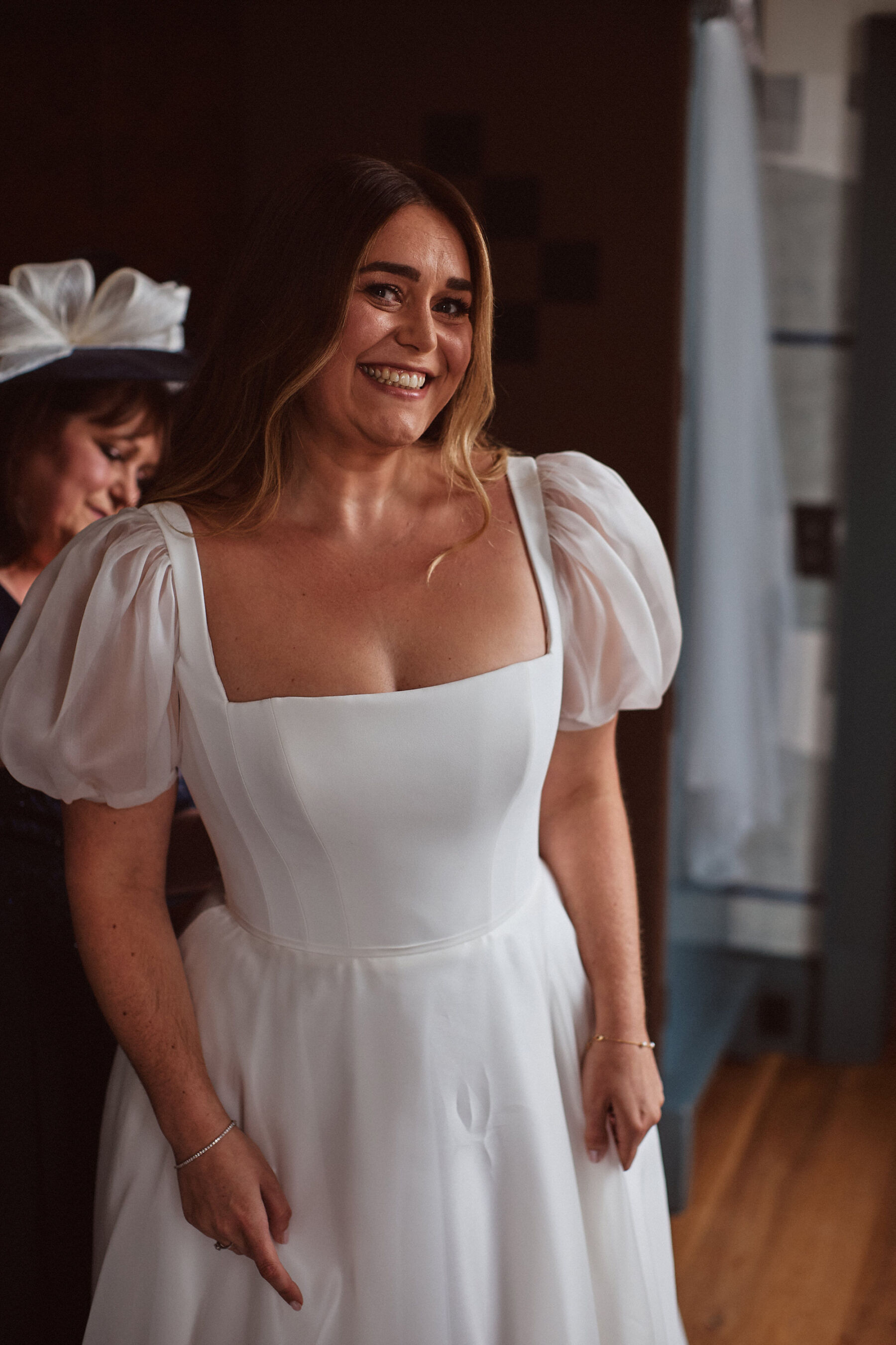 Smiling happy bride in a puff sleeve Suzanne Neville wedding dress.
