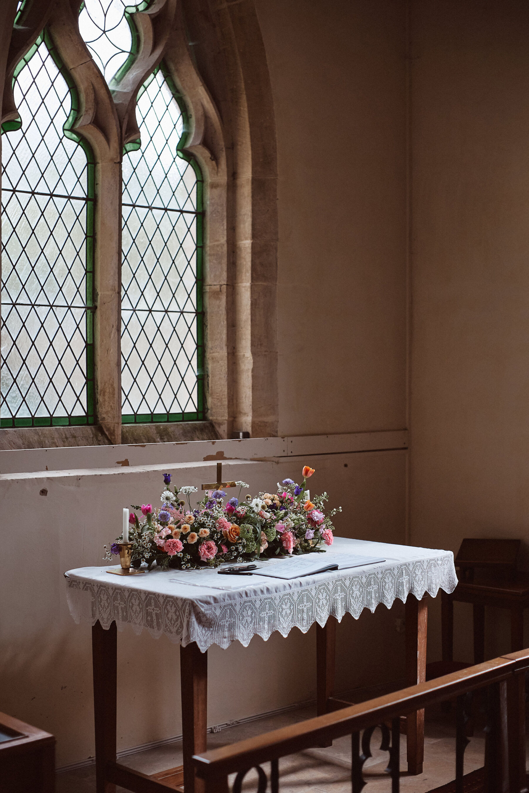 A long and low floral decoration for the registrar's table inside church.