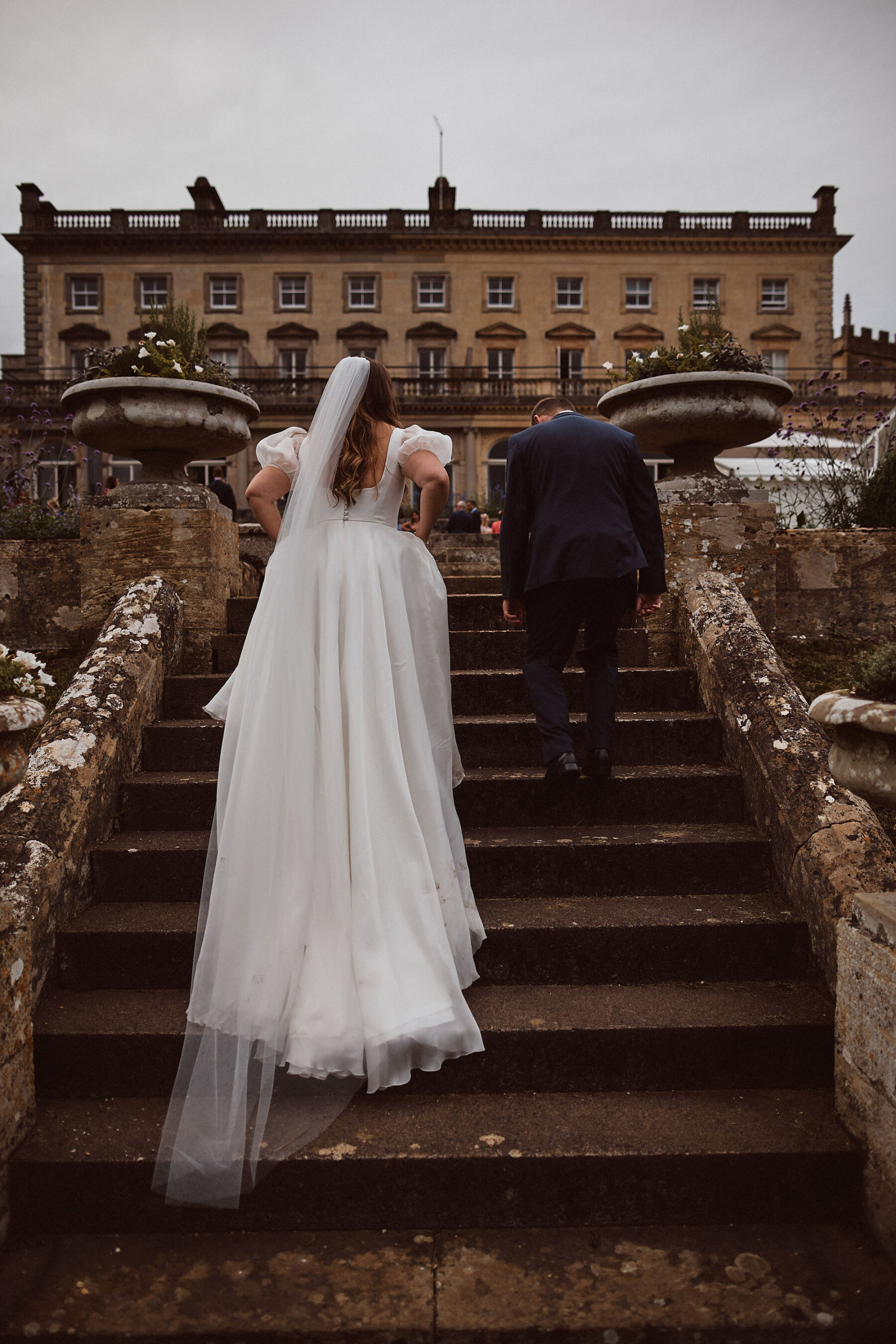 Bride and groom walking up the steps in the gardens of Cowley Manor in The Cotswolds.