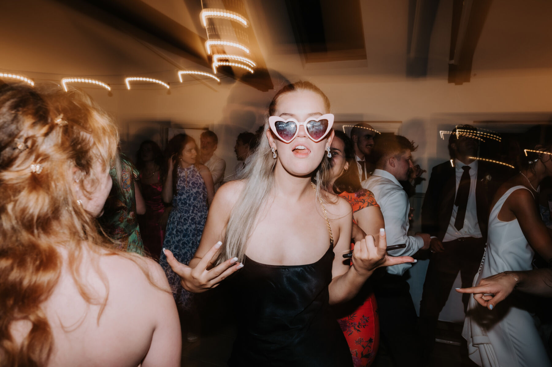 Wedding guest wearing heart sunglasses dancing on the dance floor