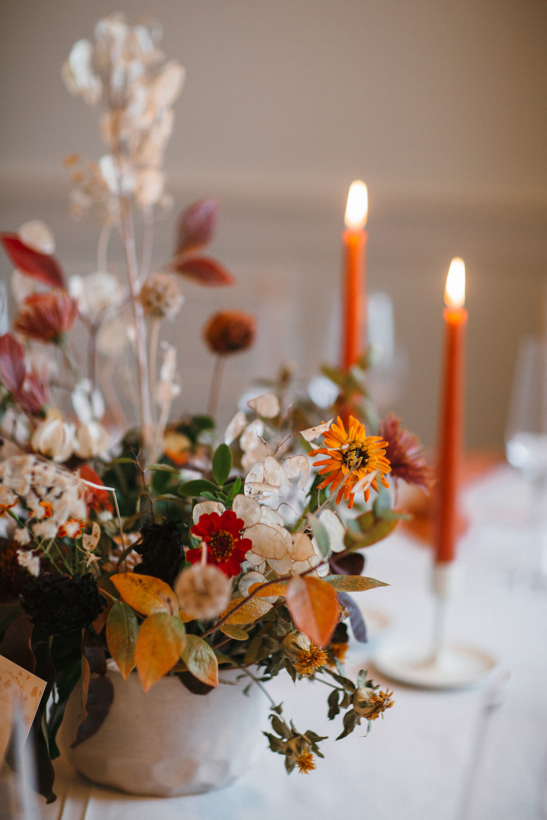 Tall orange taper candles and Autumn wedding flowers.