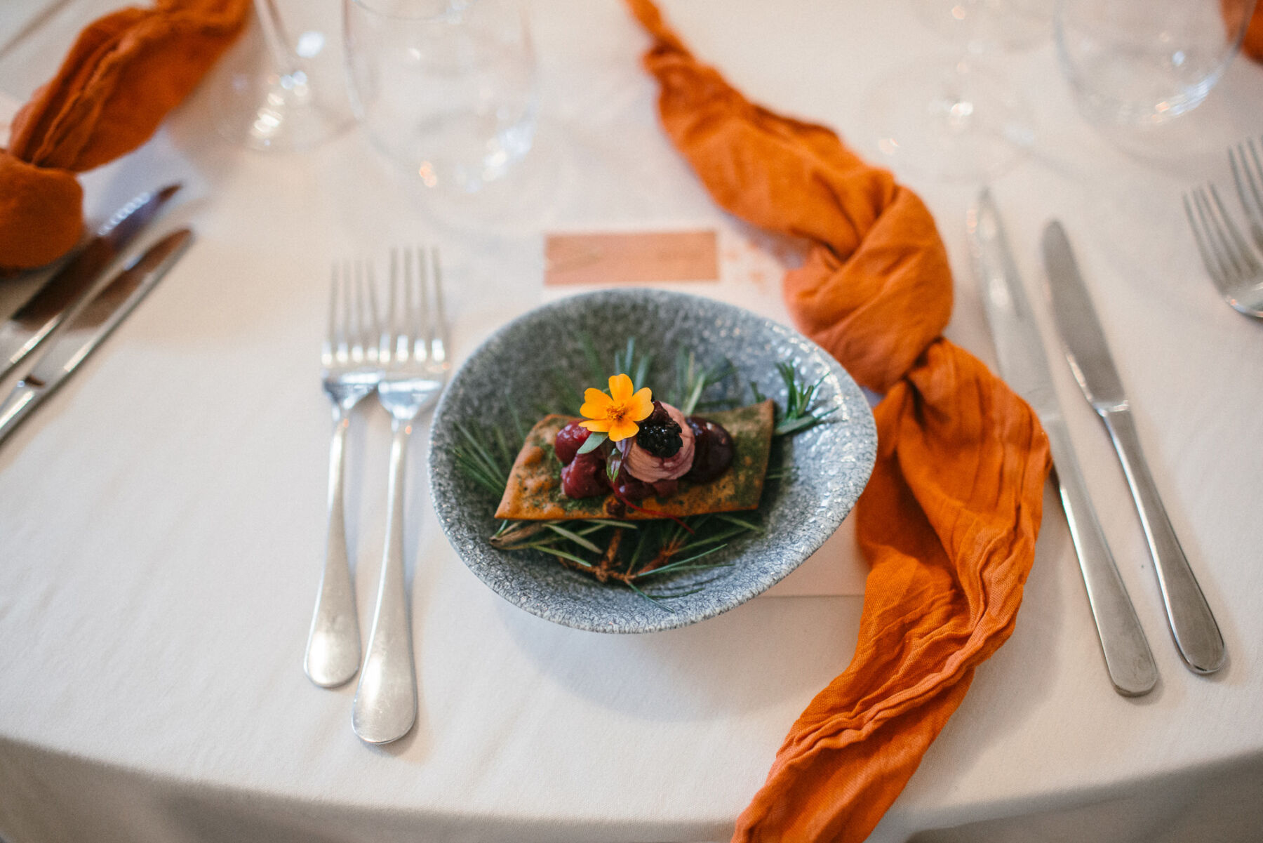 Creative wedding food decorated with edible flowers. Pottery dish and burned orange napkins.