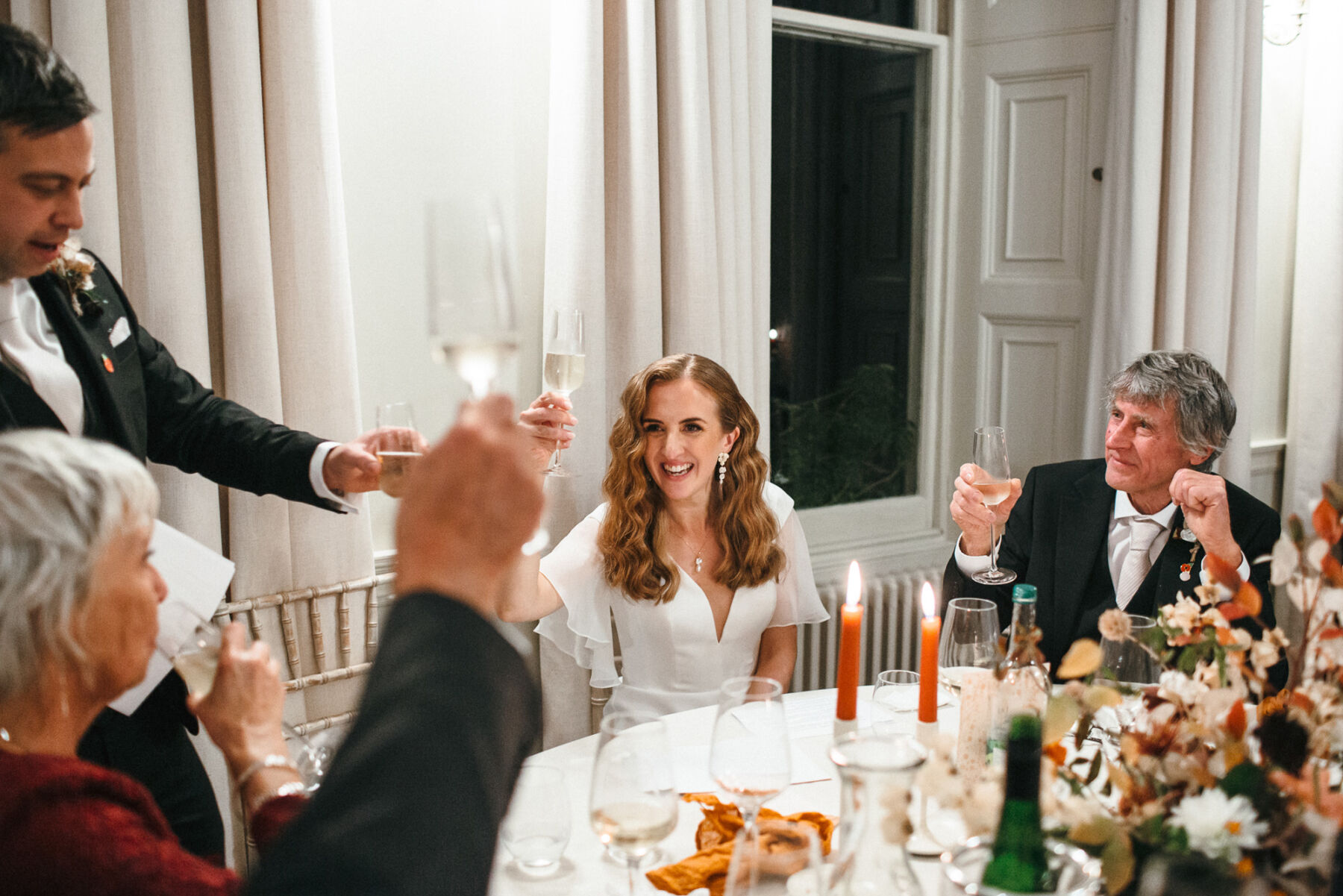 Bride and groom chinking champagne glasses during wedding speeches.