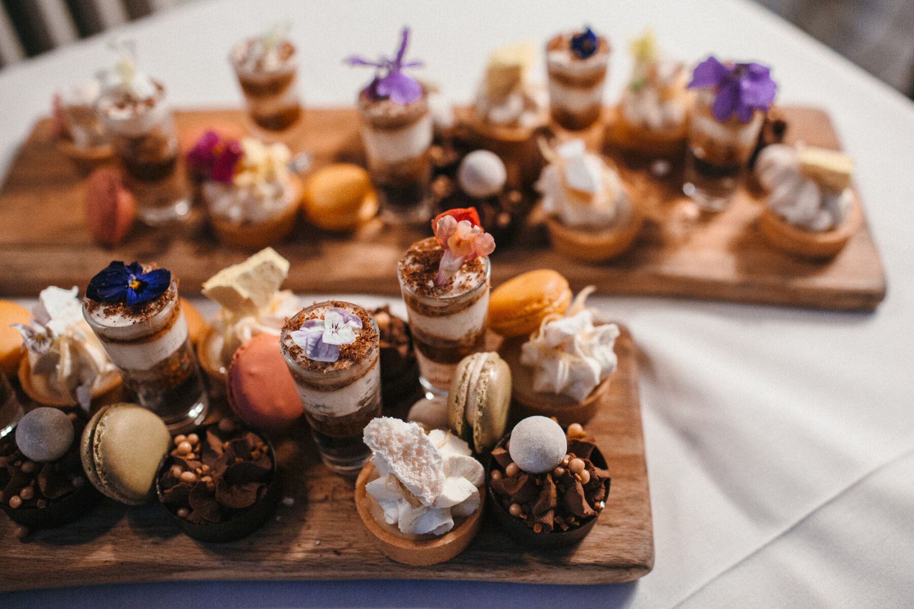 Creative wedding desserts and canapes on wooden trays including edible flowers.
