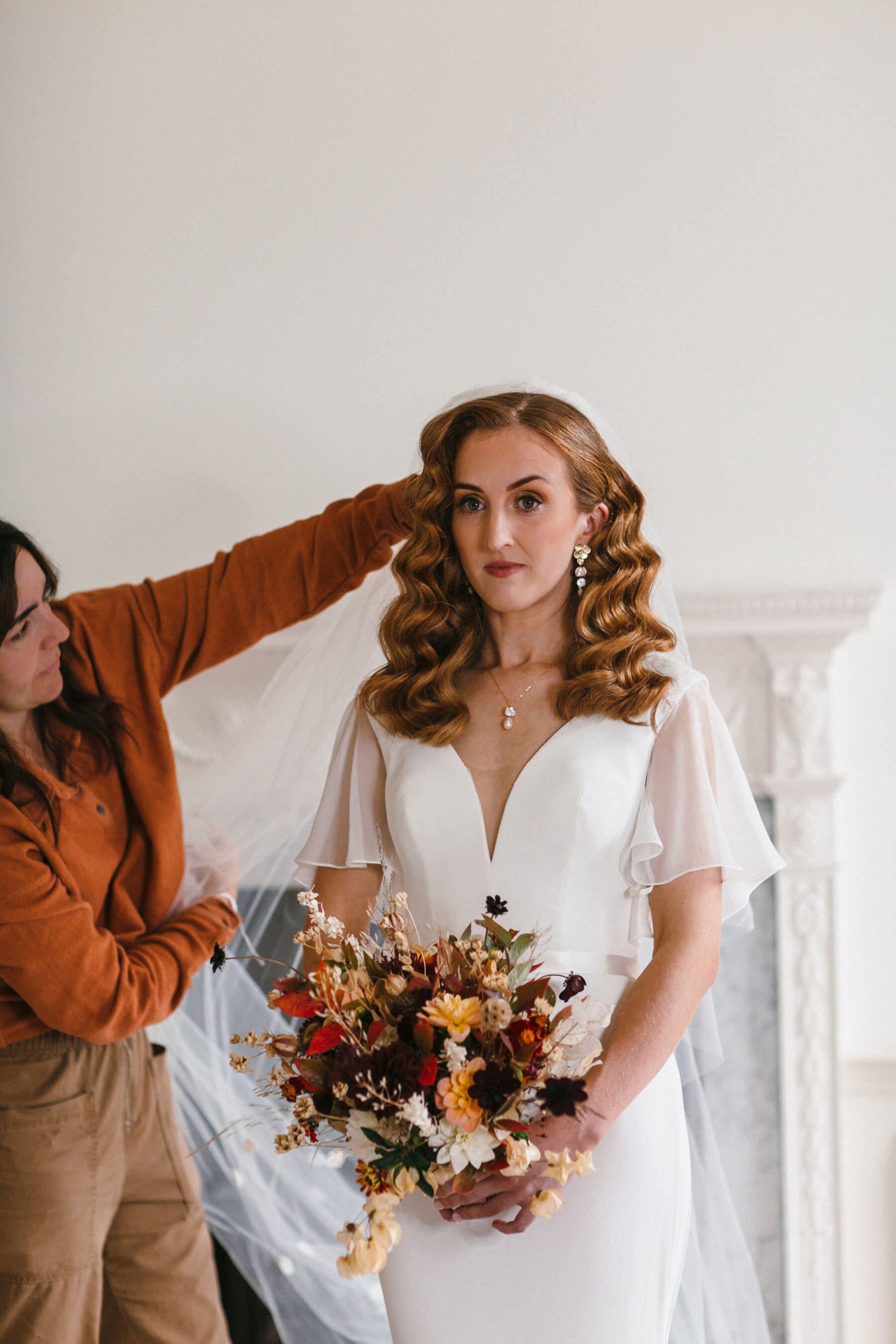 Modern bride with long wavy hair. Marcel waves, carrying an elegant Autumn wedding bouquet. 