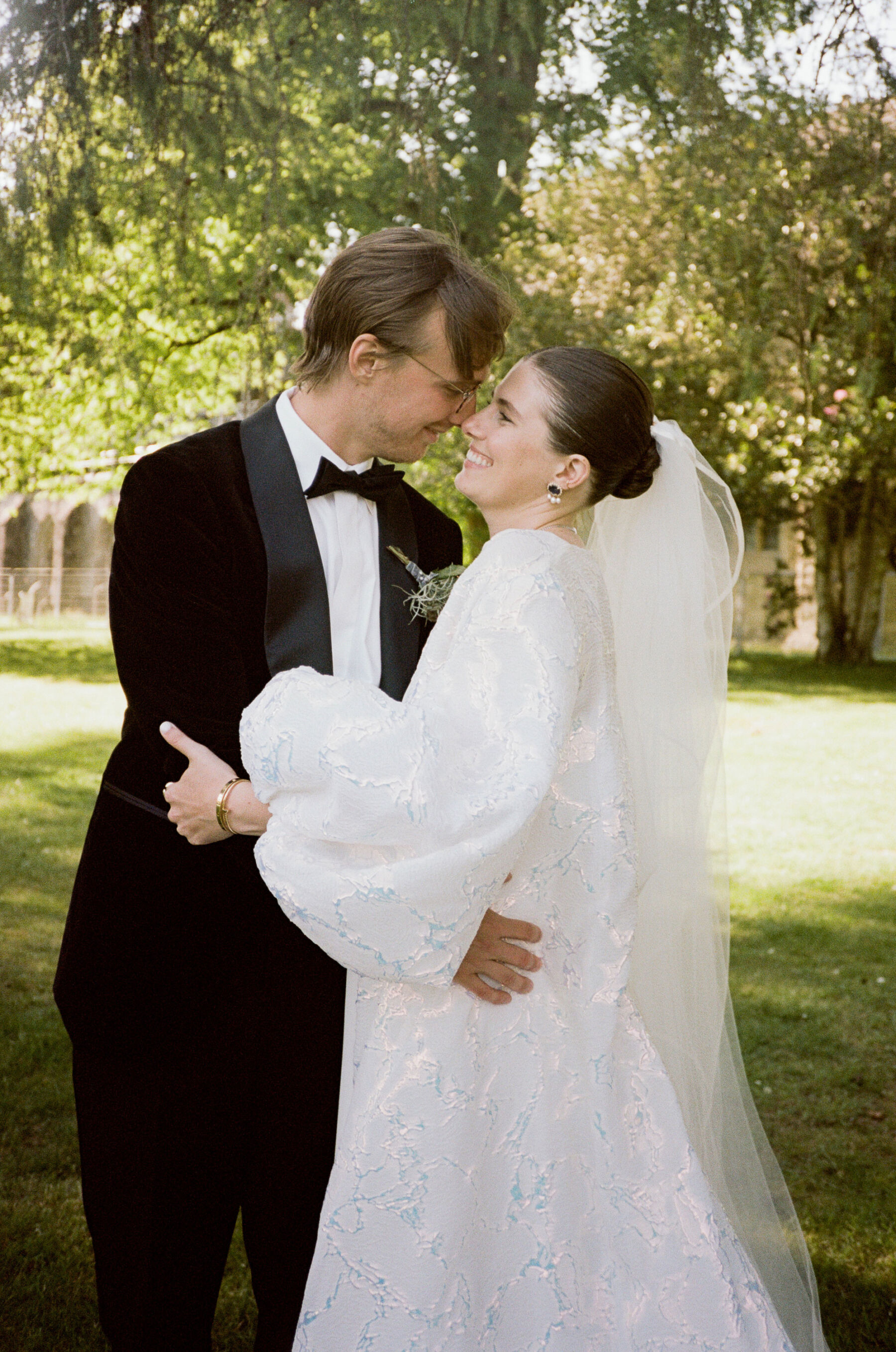 Bride in billow sleeved wedding coat by Jesus Peiro, embracing her groom in black tie.