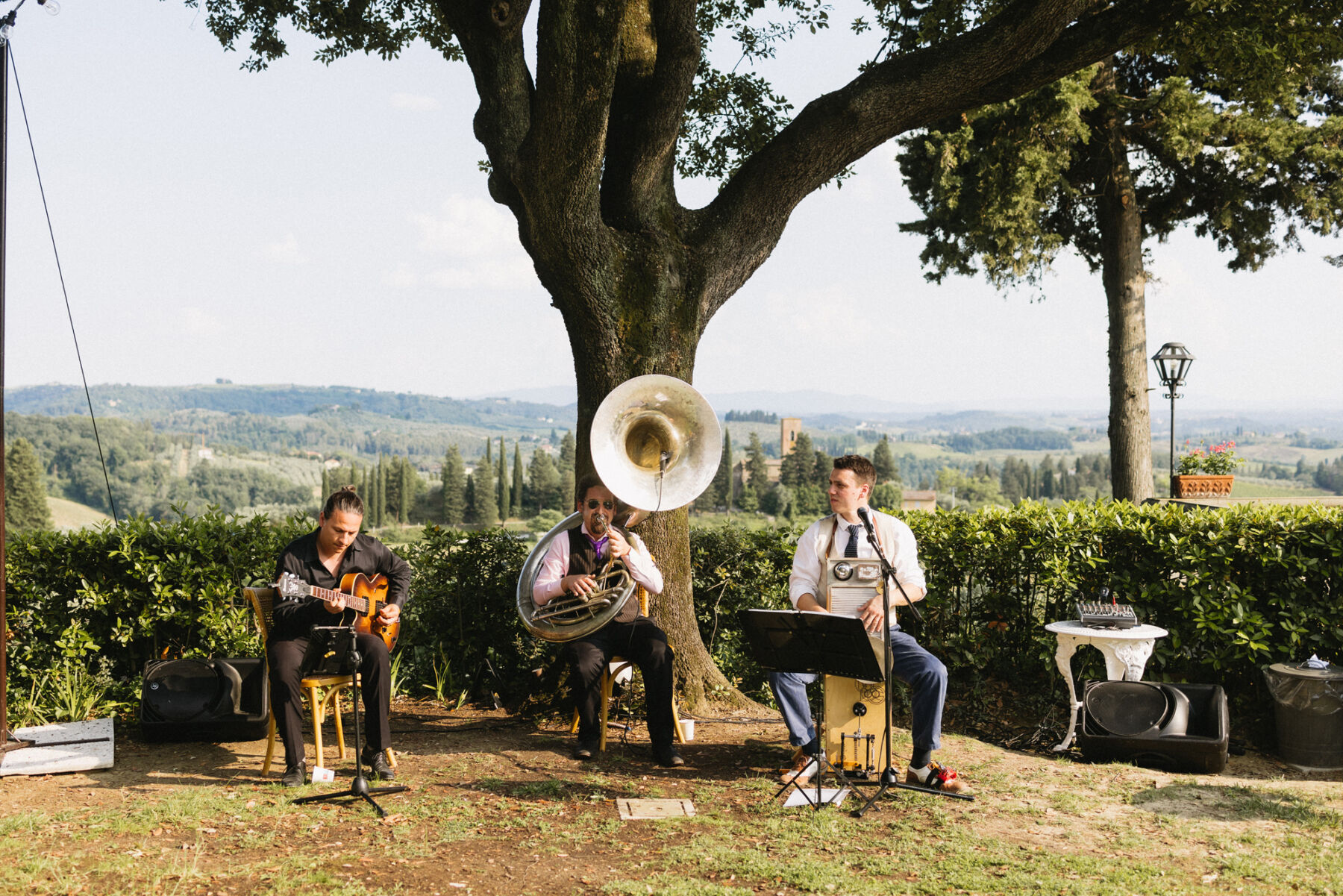 3 piece brass band seated in the gardens at an Italian wedding in Tuscany. 