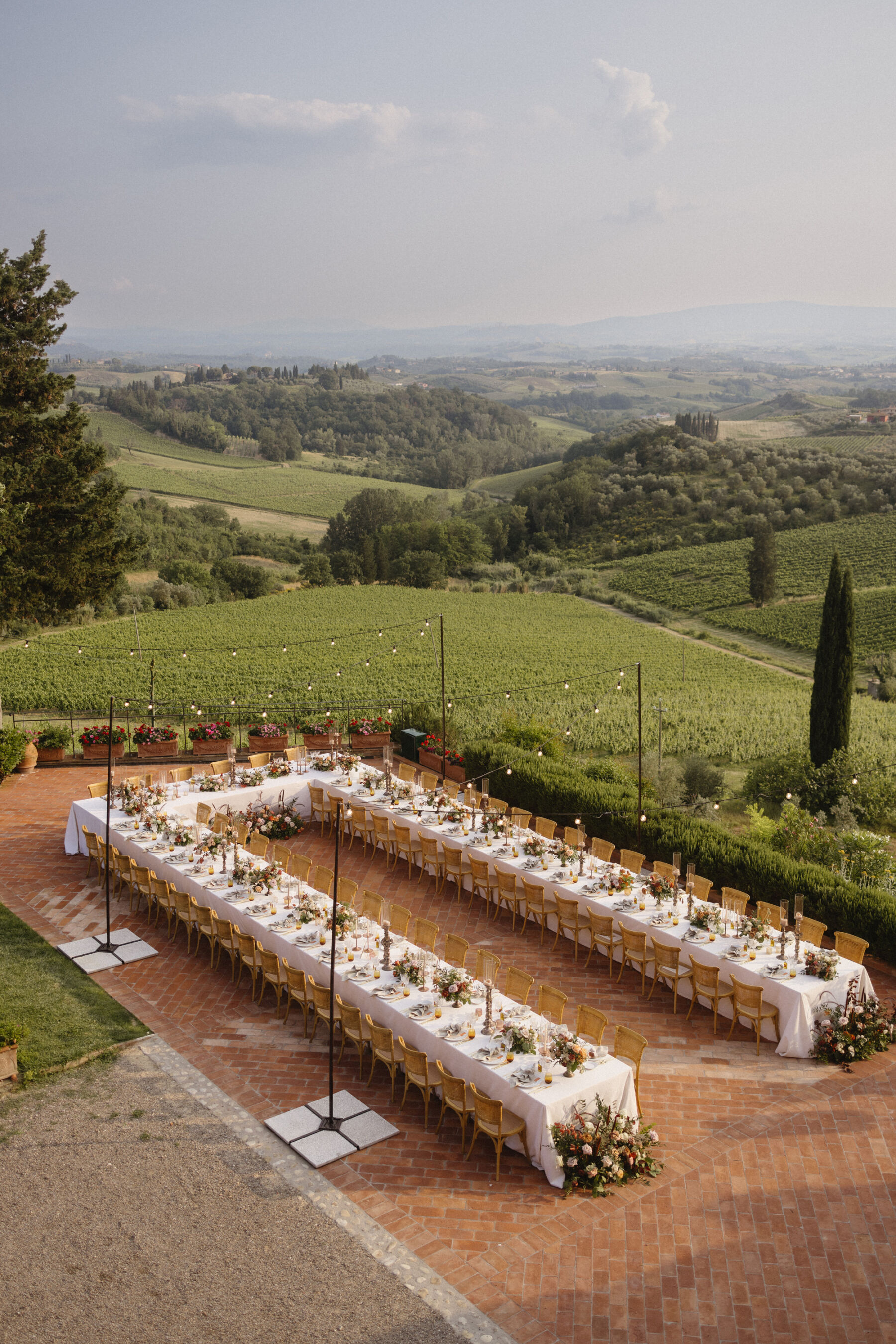 Long dining tables arrange for an outdoor wedding reception in Tuscany, Italy. Rolling hills captured in the backdrop.