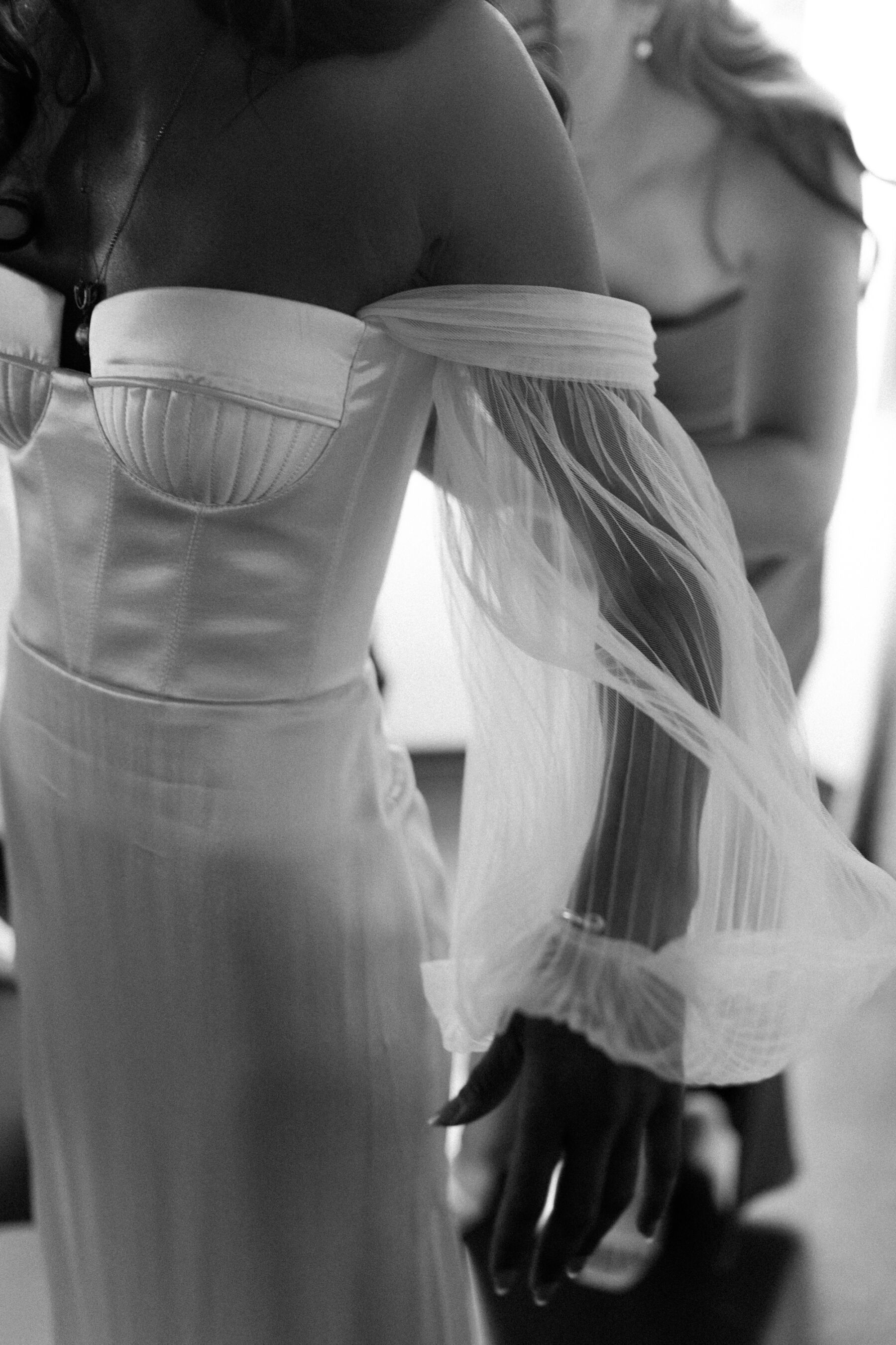 Black and white close up shot of a bride wearing an Alena Leena wedding dress. Off the shoulder gown with cupped breast and floaty, detachable tulle sleeves.