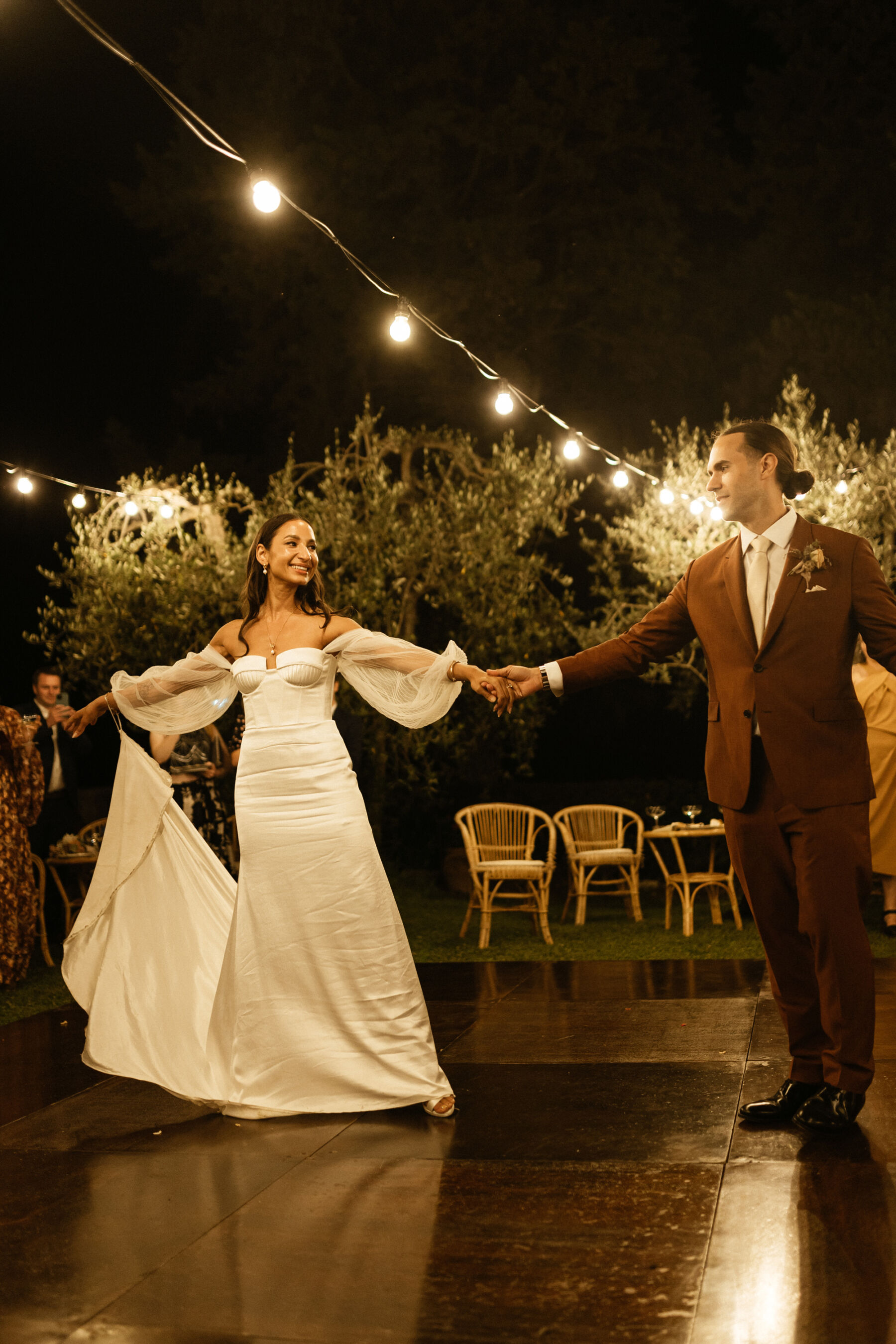 Modern bride and groom on the dance floor. She wears a strapless Alena Leena bridal gown with detachable tulle sleeves. Groom wears Paul Smith.