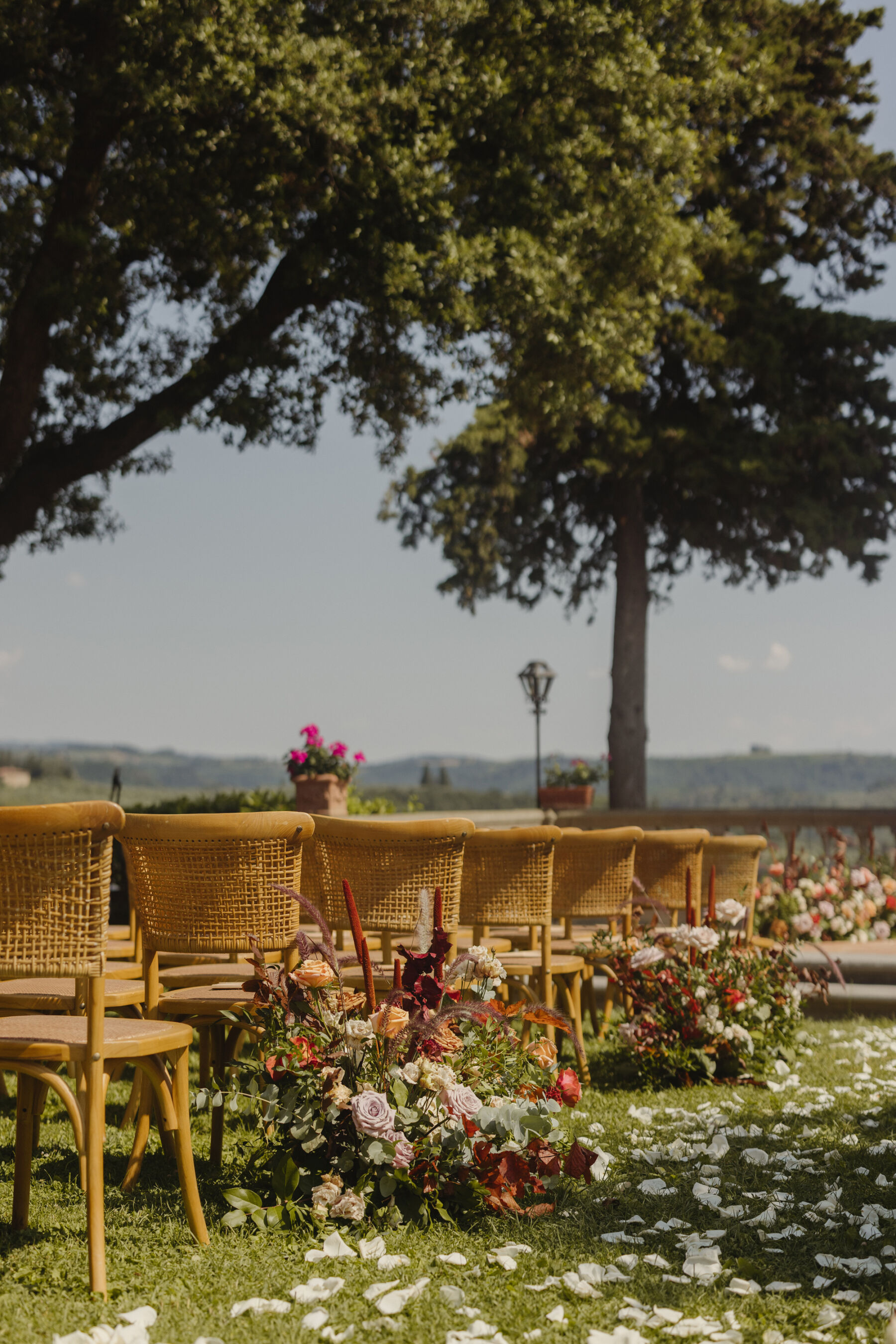 Outdoor wedding in Italy. The wedding aisle is strewn with rose petals and each other aisle end has a beautiful ground based floral installation.