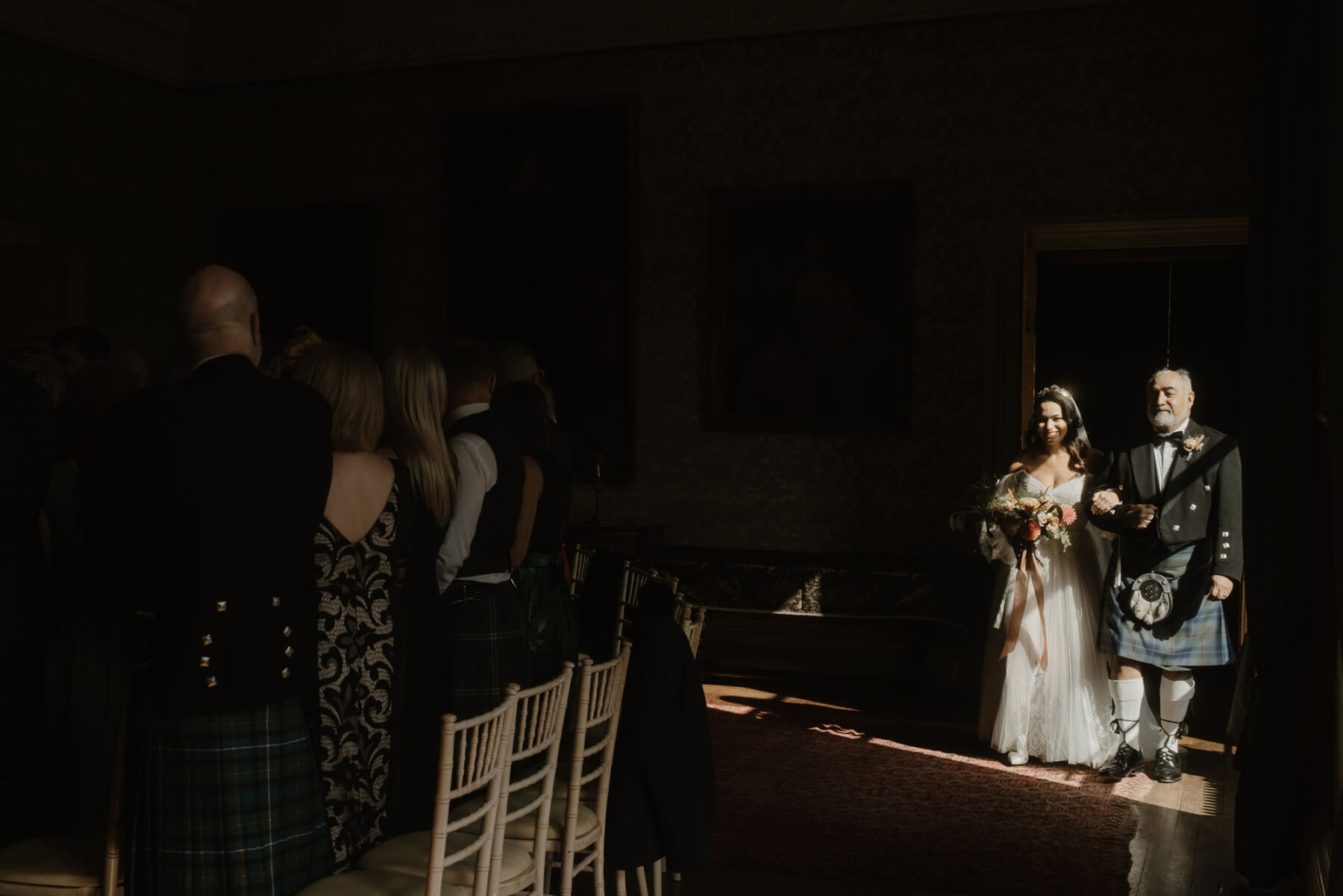 Bride arriving at her wedding ceremony at Cambo Estate, with her father wearing a kilt. She carries an Autumn wedding bouquet.