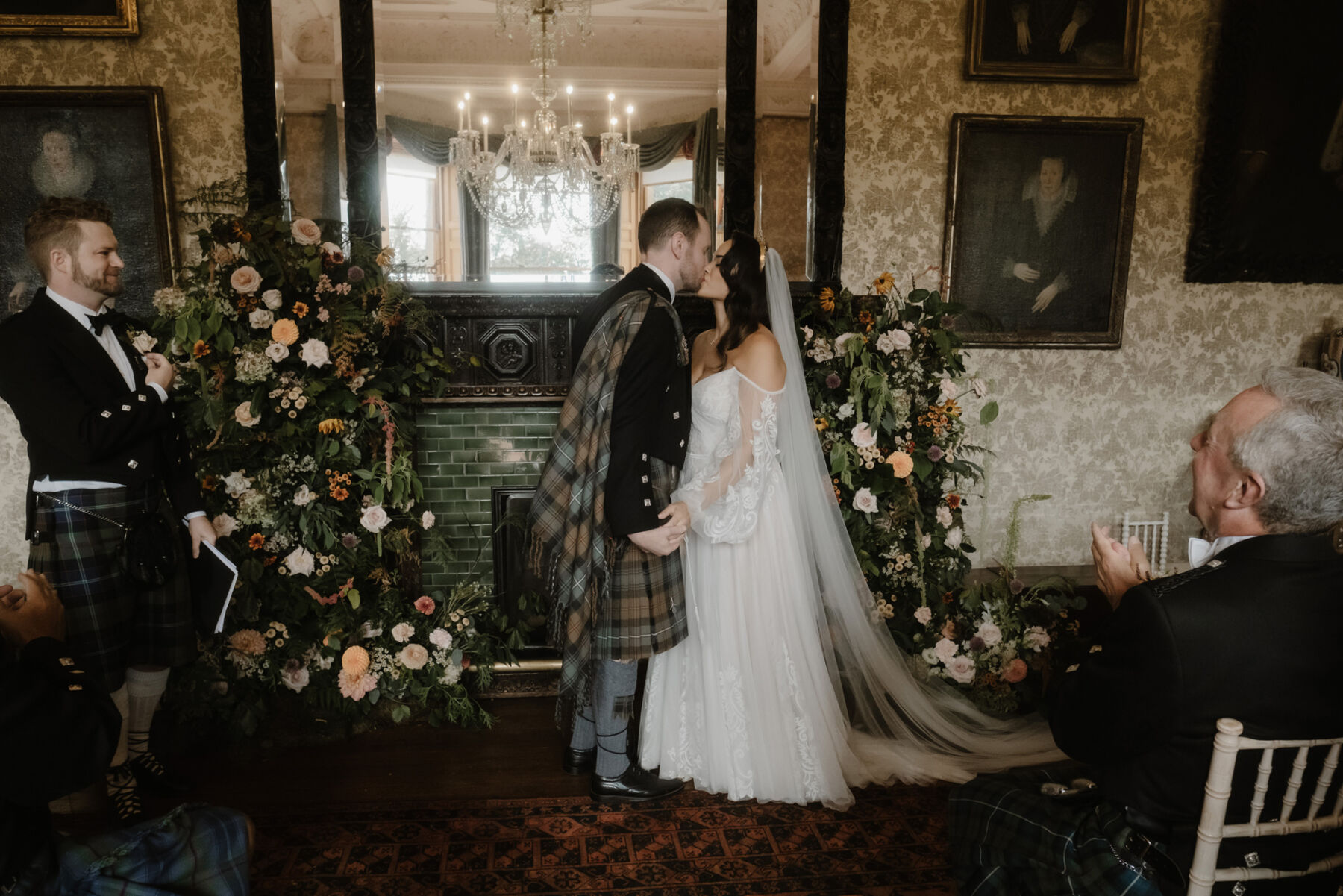 Bride and groom kissing after being pronounced man and wife at their wedding at Cambo Estate in Scotland. The groom wears a tartan fly plaid and kilt. Bride wears a Willowby by Watters wedding dress.