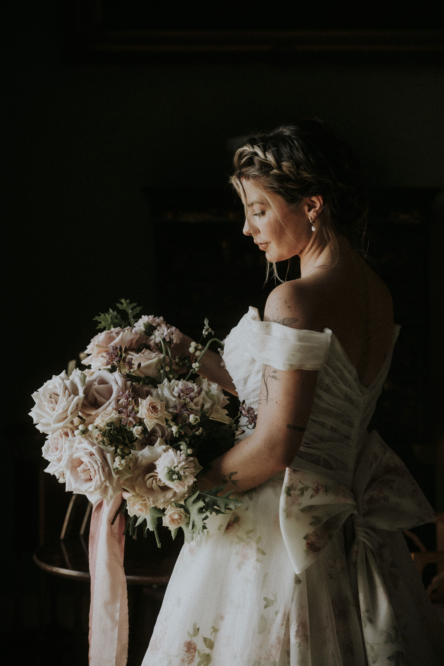 Bride wearing a Dutch Crown plait, a romantic floral wedding dress by Josephine Scott London & carrying a bouquet of blown out pastel roses with a silk ribbon.