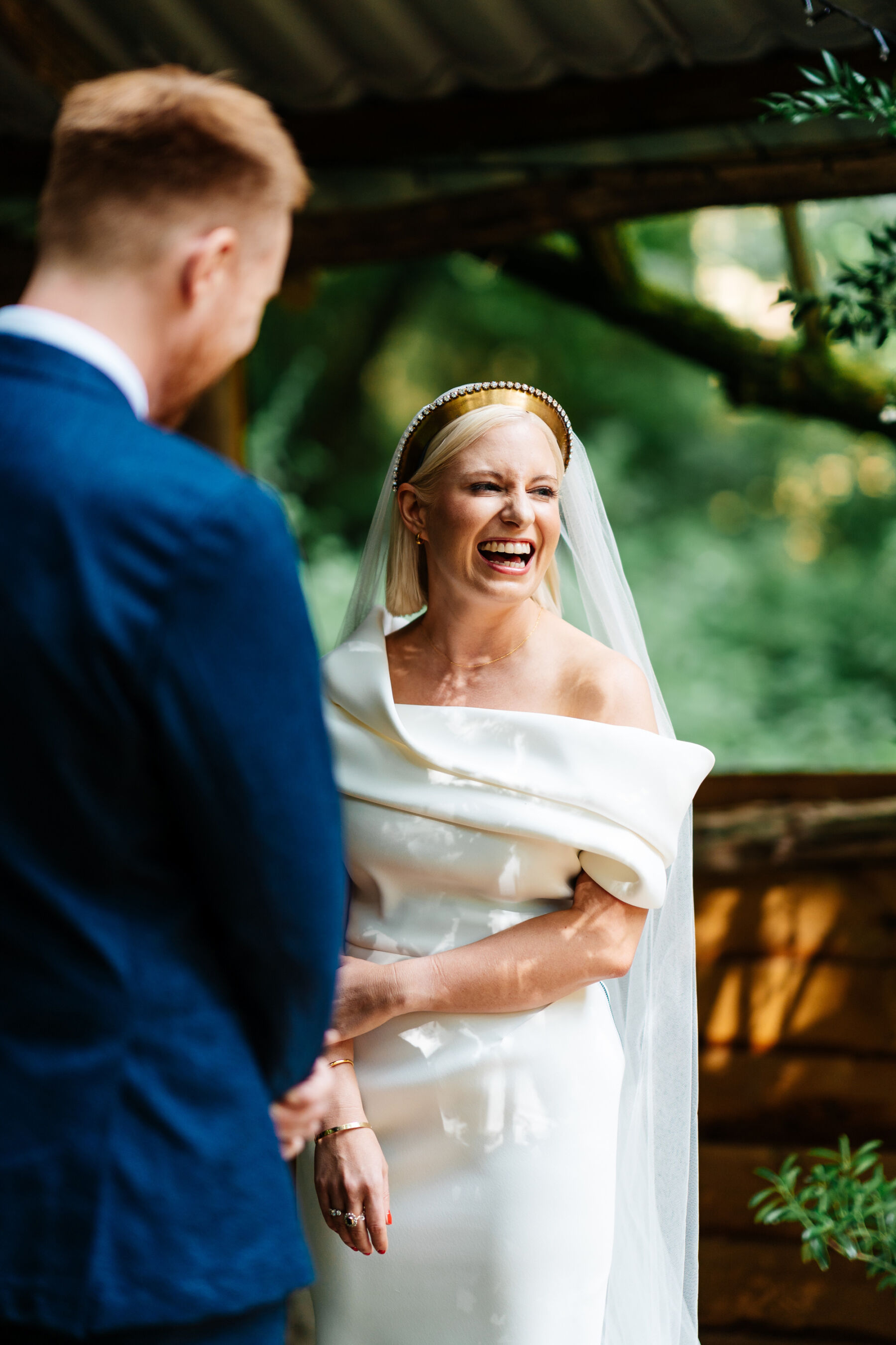 Laughing happy bride wearing Toni Maticevski contemporary wedding dress and gold headpiece.