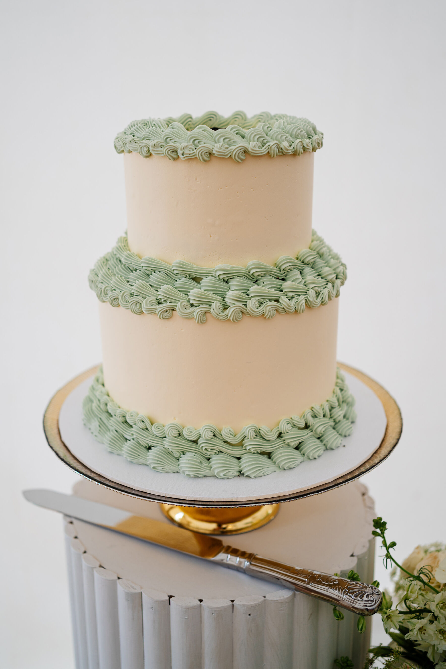 Simple 2 tier wedding cake with pale green frilly icing at the bases.