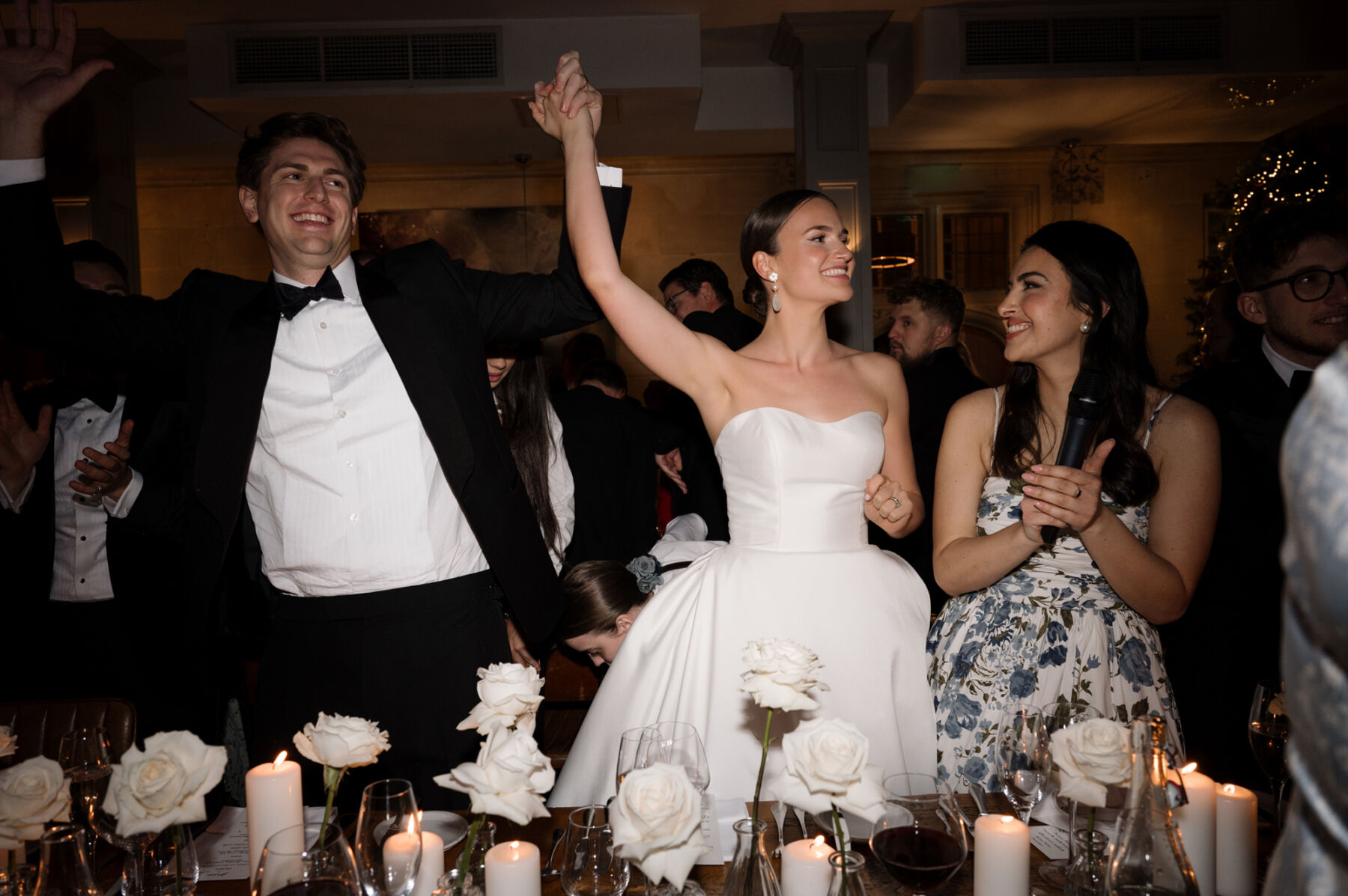 An Elegant Black Tie Wedding at Hampton Manor in Birmingham, with a Badgley Mischka Gown 53 Happy bride and groom at their wedding reception at Hampton Manor, they are surrounded by smiling friends, white roses and candles. Taylor Hughes Photography.