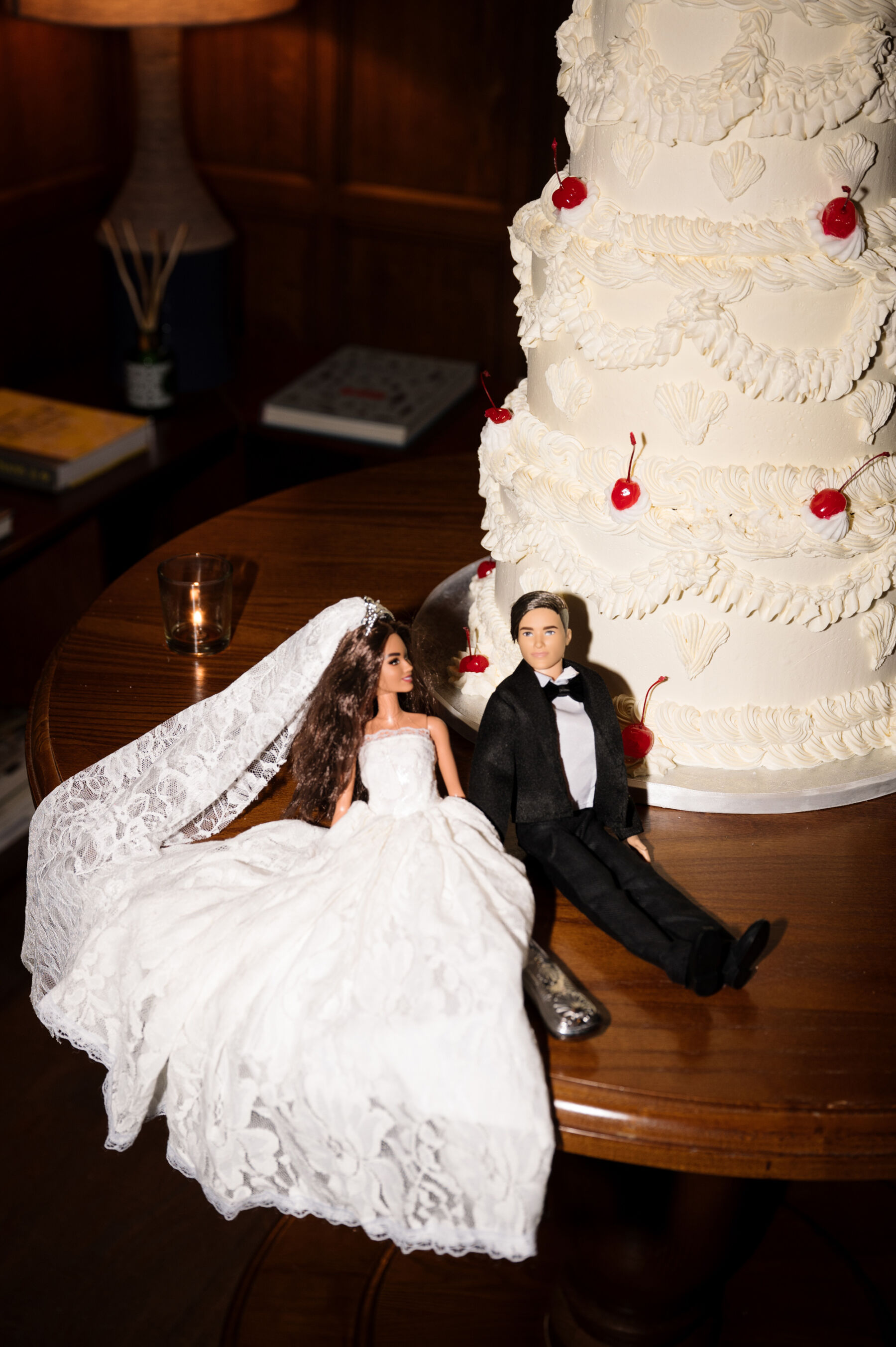 An Elegant Black Tie Wedding at Hampton Manor in Birmingham, with a Badgley Mischka Gown 54 Barbie doll in a wedding dress next to a Ken doll groom, positioned near to a wedding cake with retro frilly icing and cherries. Taylor Hughes Photography.