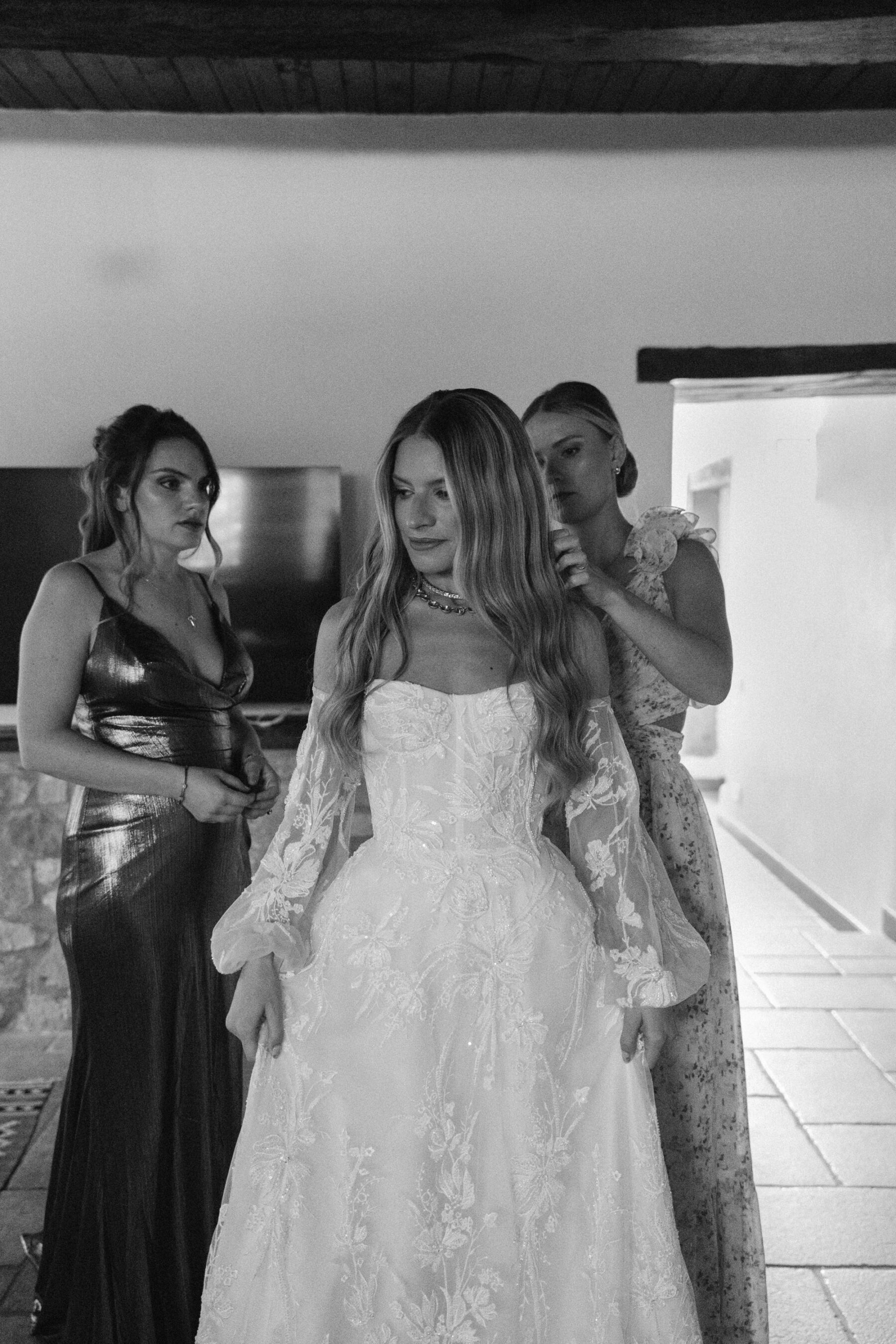 Mikaela in Alena Leena For Her Elegant Italian Wedding at Villa Fattoria di Vibio 12 Bride getting in to her Alena Leena bridal gown with removable sleeves. Her bridesmaids are assisting her into her dress. Photography by Stefano Santucci.