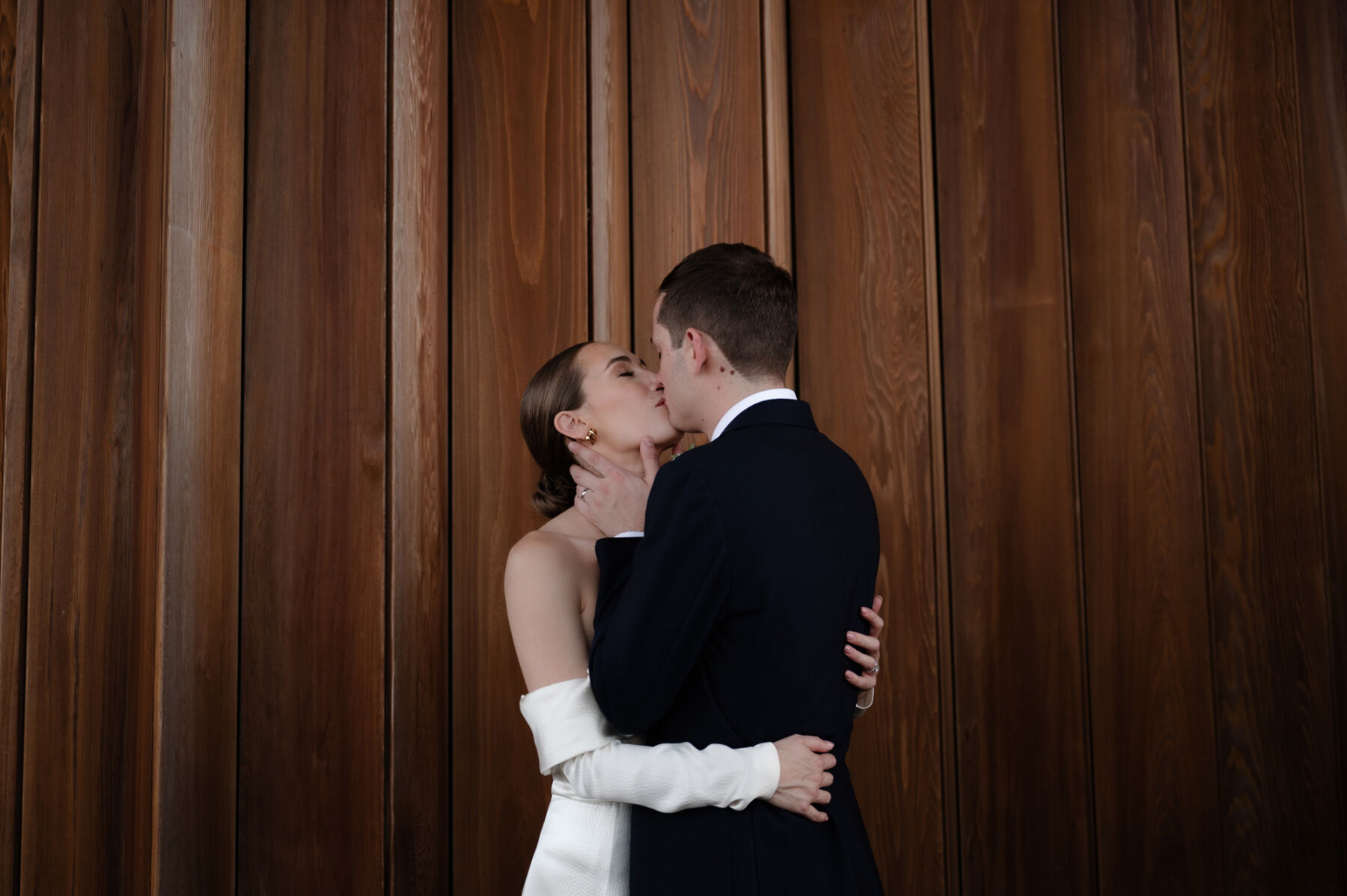 A Chic London Wedding: Soraya's Nikeen Asar Dress Captured by Taylor-Hughes Photography 33 Bride with a low bun and a Nikeen Awar bridal gown being tenderly kissed by her groom. Taylor-Hughes Photography.