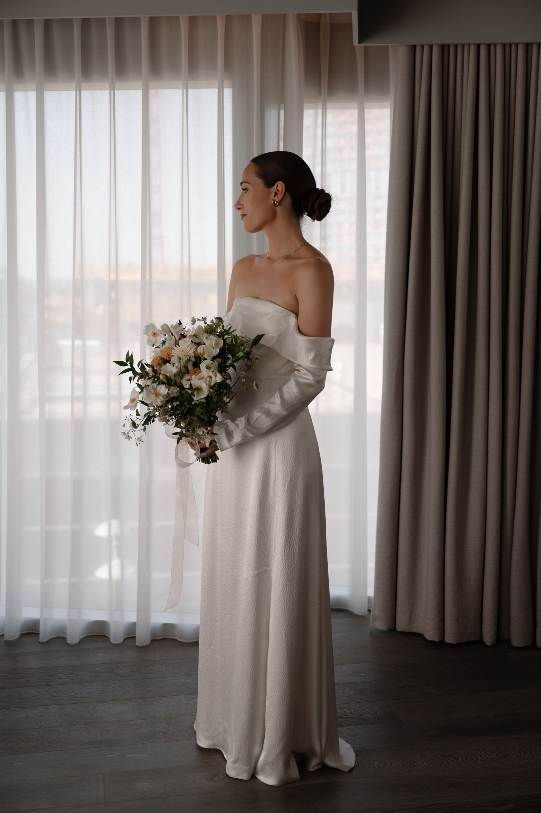 A Chic London Wedding: Soraya's Nikeen Asar Dress Captured by Taylor-Hughes Photography 6 Modern bride in an off the shoulder bridal gown by Nikeen Asar. She carries a large modern bridal bouquet in neutral tones. Taylor-Hughes Photography.