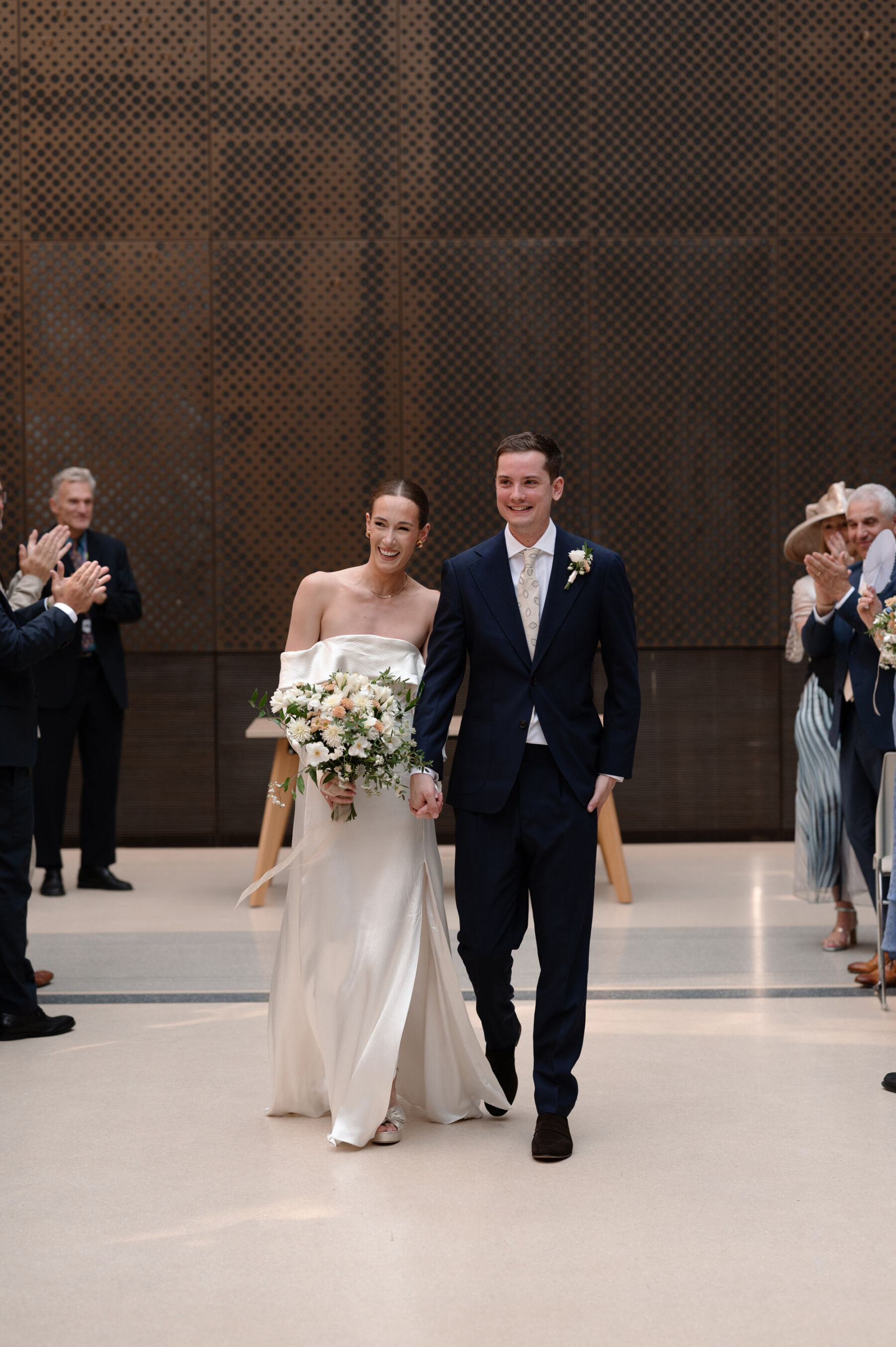 A Chic London Wedding: Soraya's Nikeen Asar Dress Captured by Taylor-Hughes Photography 14 Bride and groom walking back down the aisle at The Atrium at Hackney Town Hall. The bride wears a Nikeen Asar wedding dress. Taylor-Hughes Photography.