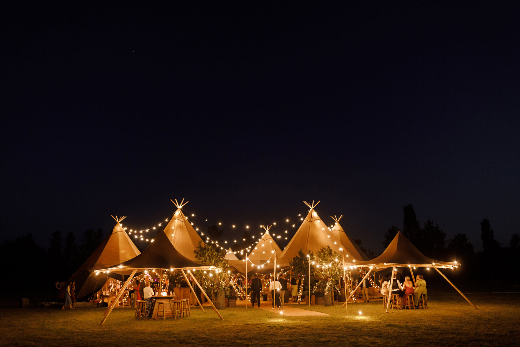 Wedding tipis lit up at night tie with festoon lights and fairy lights creating a beautiful warm and romantic atmosphere.