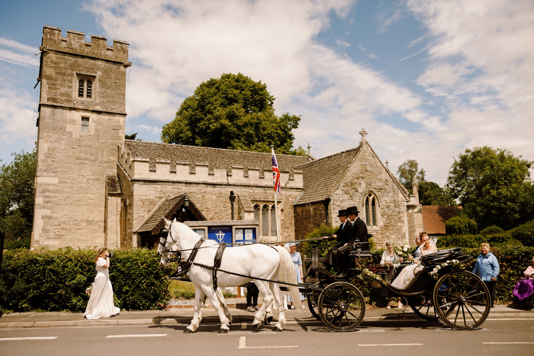 Bride being pulled by a horse and carriage on her wedding day as they approach the church.