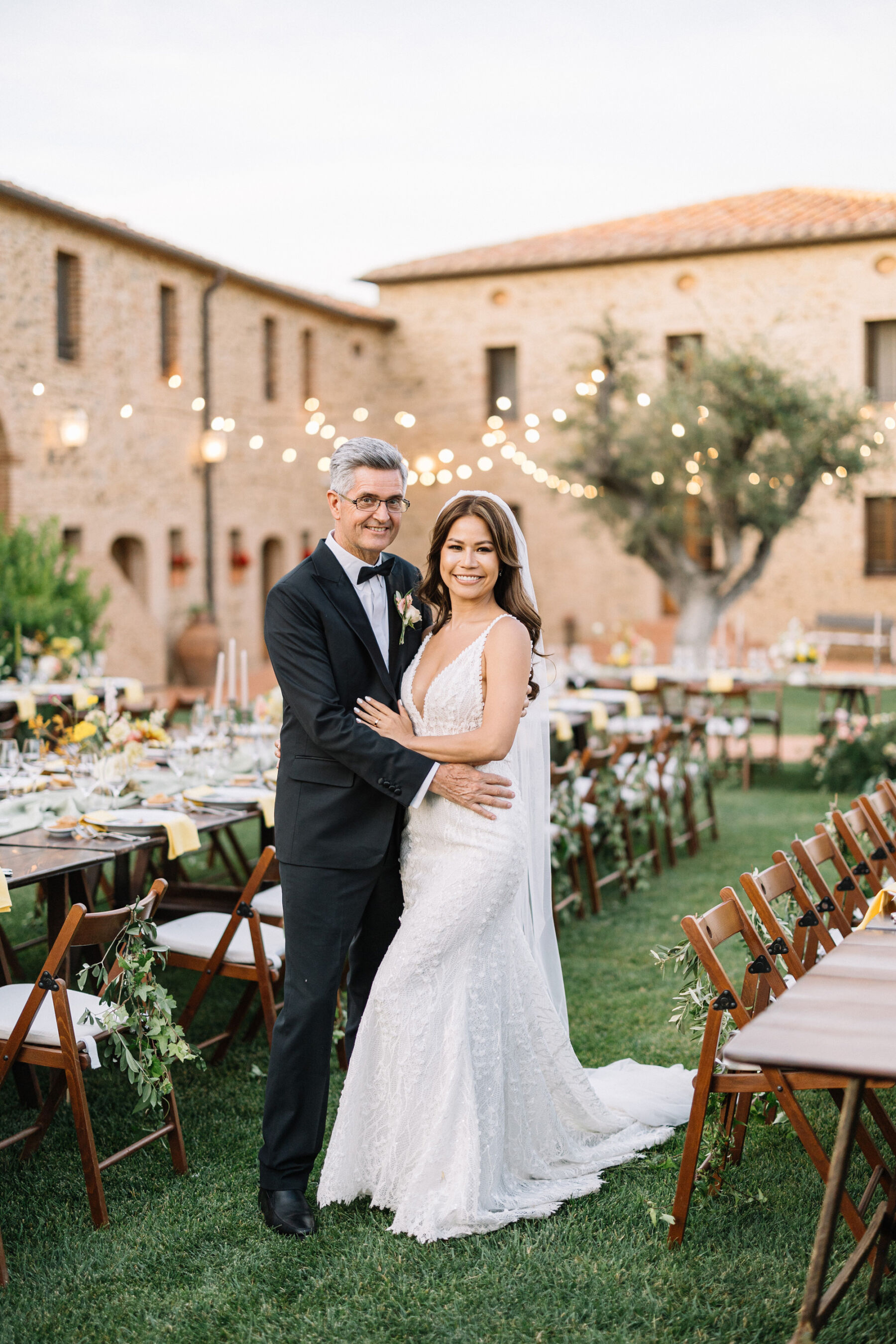 A Professional Wedding Planner's Wedding at Colle Massari in Tuscany, Italy 28 Bride and groom standing next to their wedding reception tables in the gardens of Colle Massari in Tuscany, Italy.