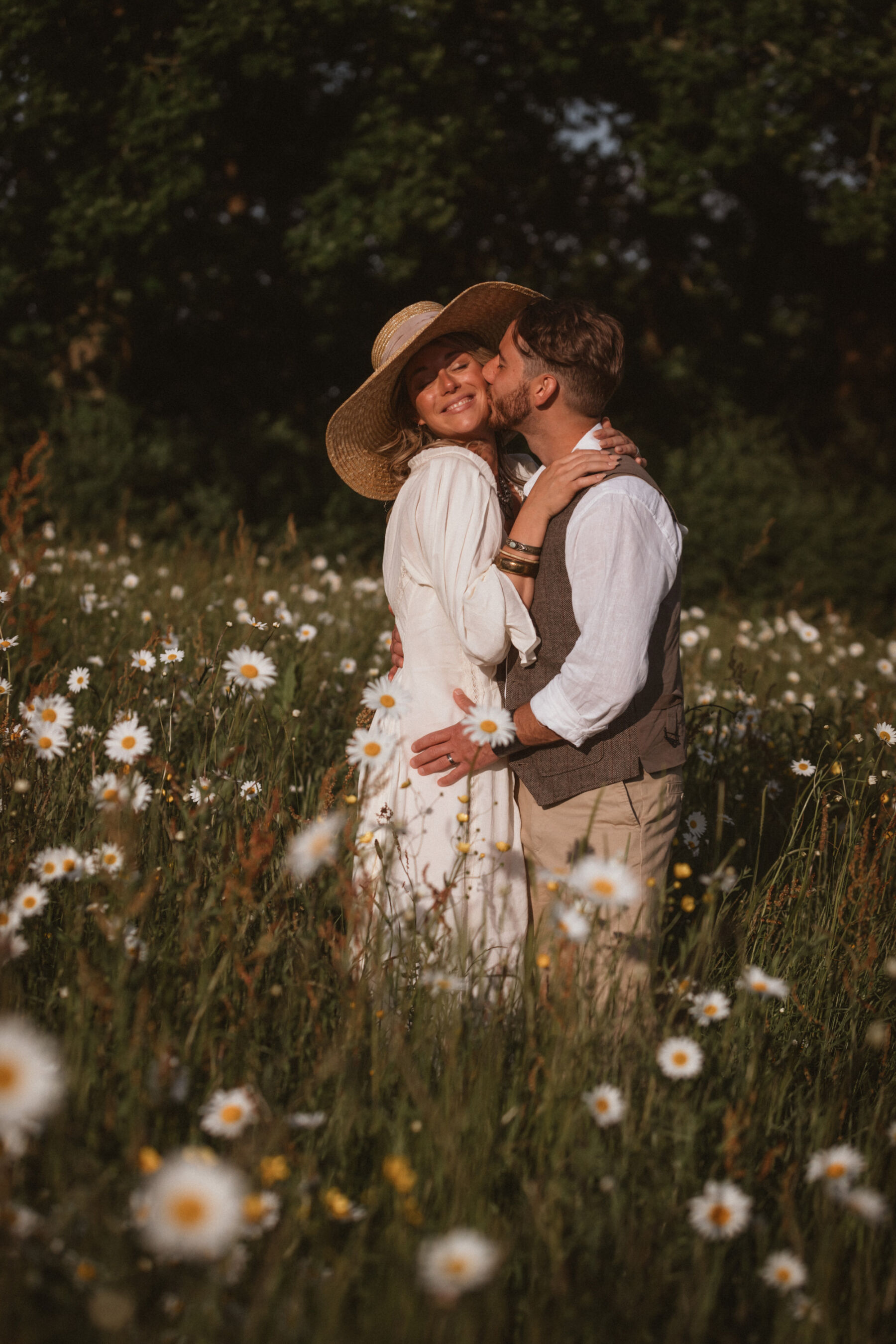 Wickerwood Farm, an Eco Friendly, Glamping Wedding Venue in East Sussex 28 Bride and groom embracing for a kiss in the middle of a wilddflower meadow at Wickerwood Farm wedding venue, East Sussex.