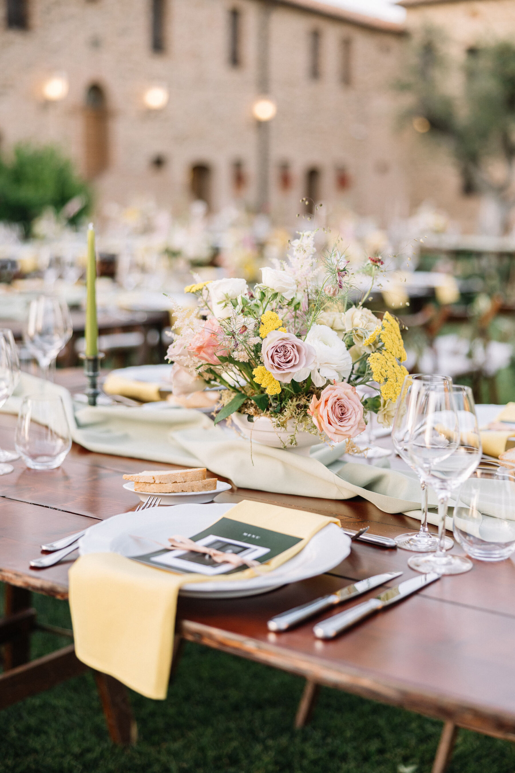 A Professional Wedding Planner's Wedding at Colle Massari in Tuscany, Italy 30 Low bowl with pastel flowers, yellow napkin. Pale green taper candles.