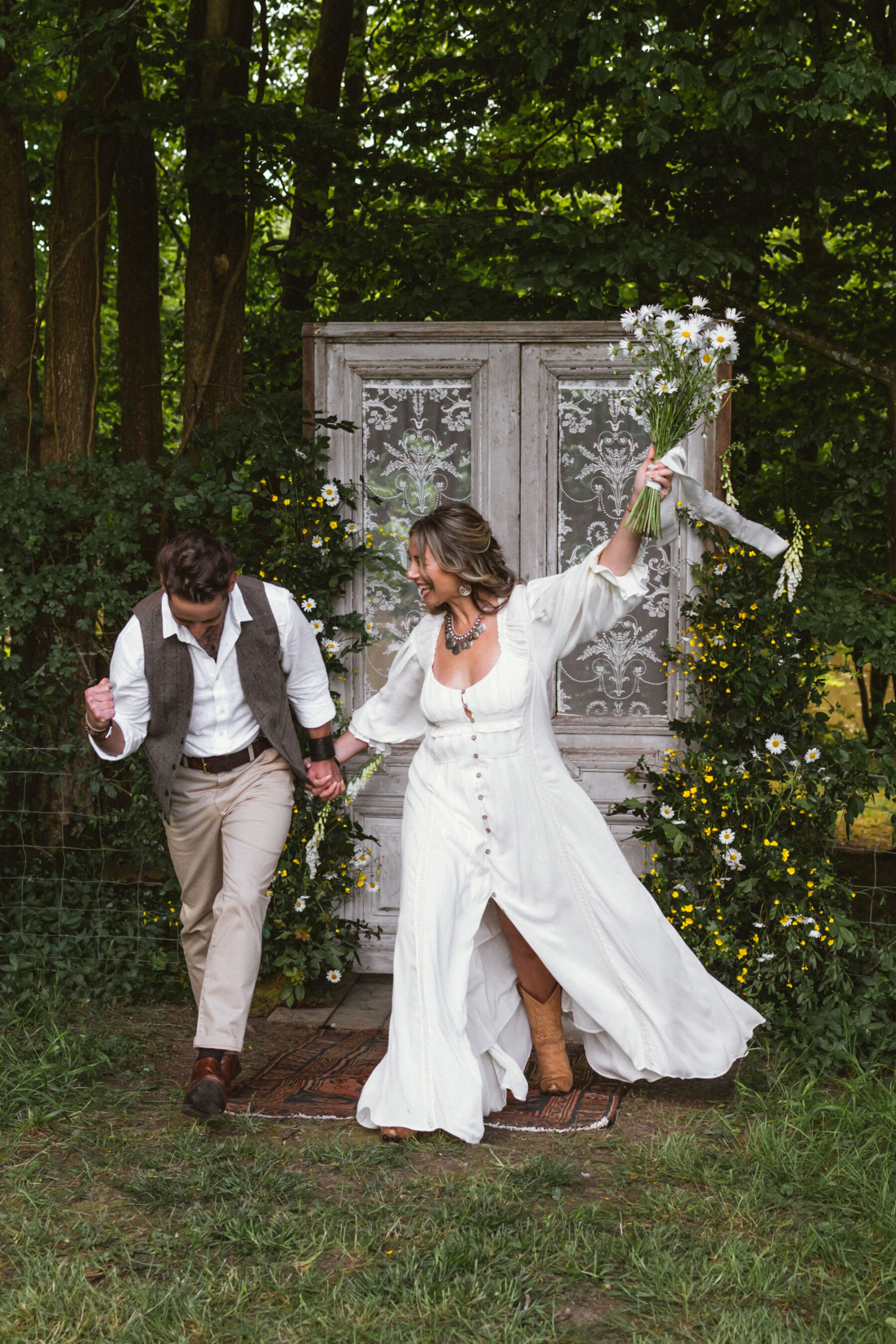 Wickerwood Farm, an Eco Friendly, Glamping Wedding Venue in East Sussex 32 Bohemian bride and groom standing by a wooden doorway inside woodland at Wickerwood Farm wedding venue in East Sussex.
