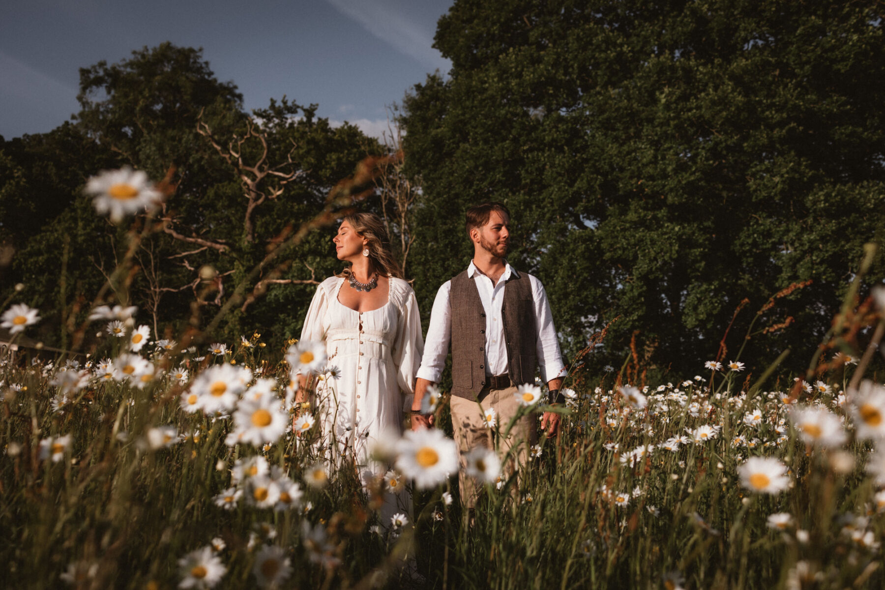 Wickerwood Farm, an Eco Friendly, Glamping Wedding Venue in East Sussex 24 Bride and groom holding hands in a field full of daisies at Wickerwood Farm wedding venue, East Sussex.