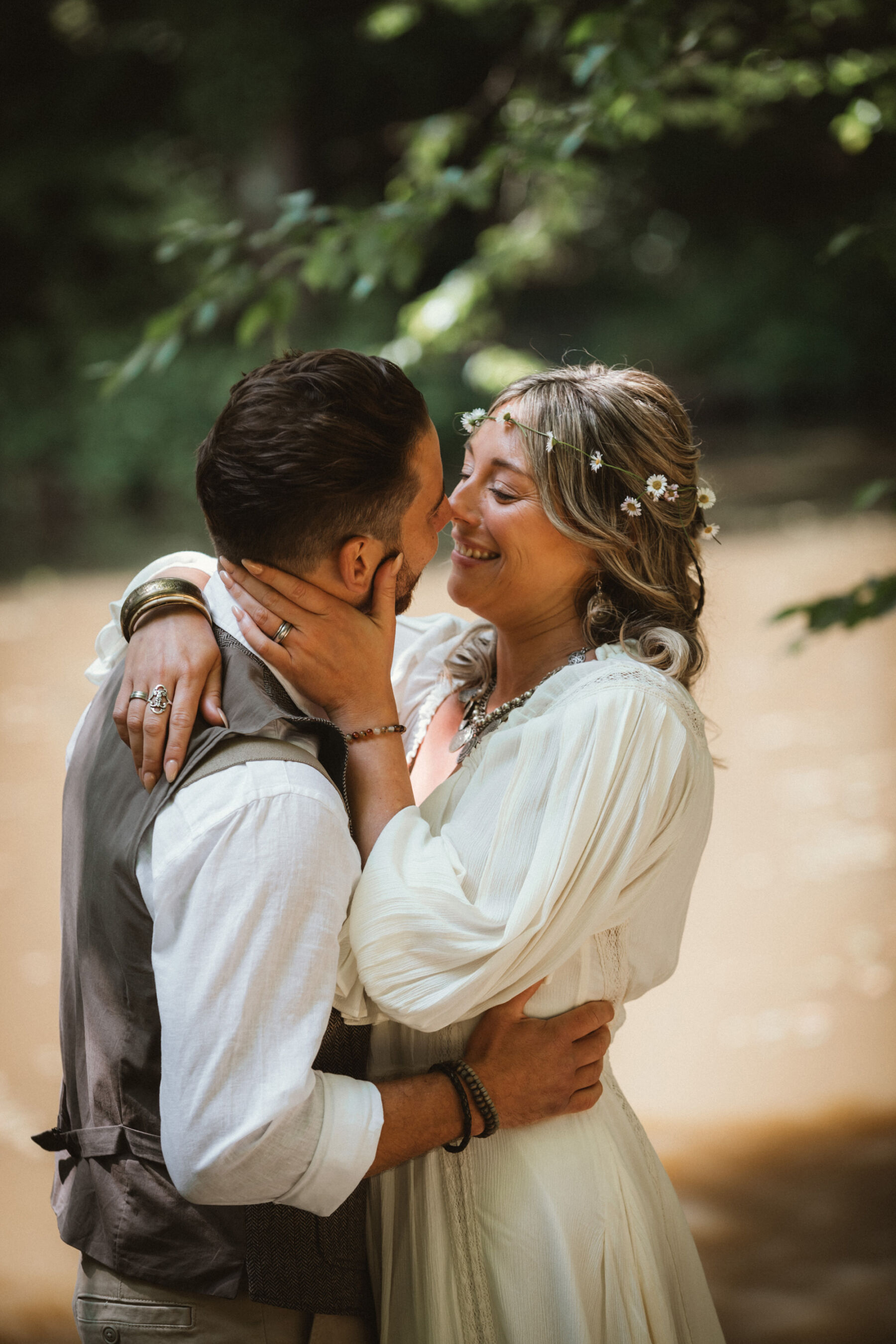 Wickerwood Farm, an Eco Friendly, Glamping Wedding Venue in East Sussex 10 Bride with a daisy chain headpiece and Free People white dress, embracing her groom in a tweed waistcoat. They are standing by the river where they have had an outdoor wedding ceremony.