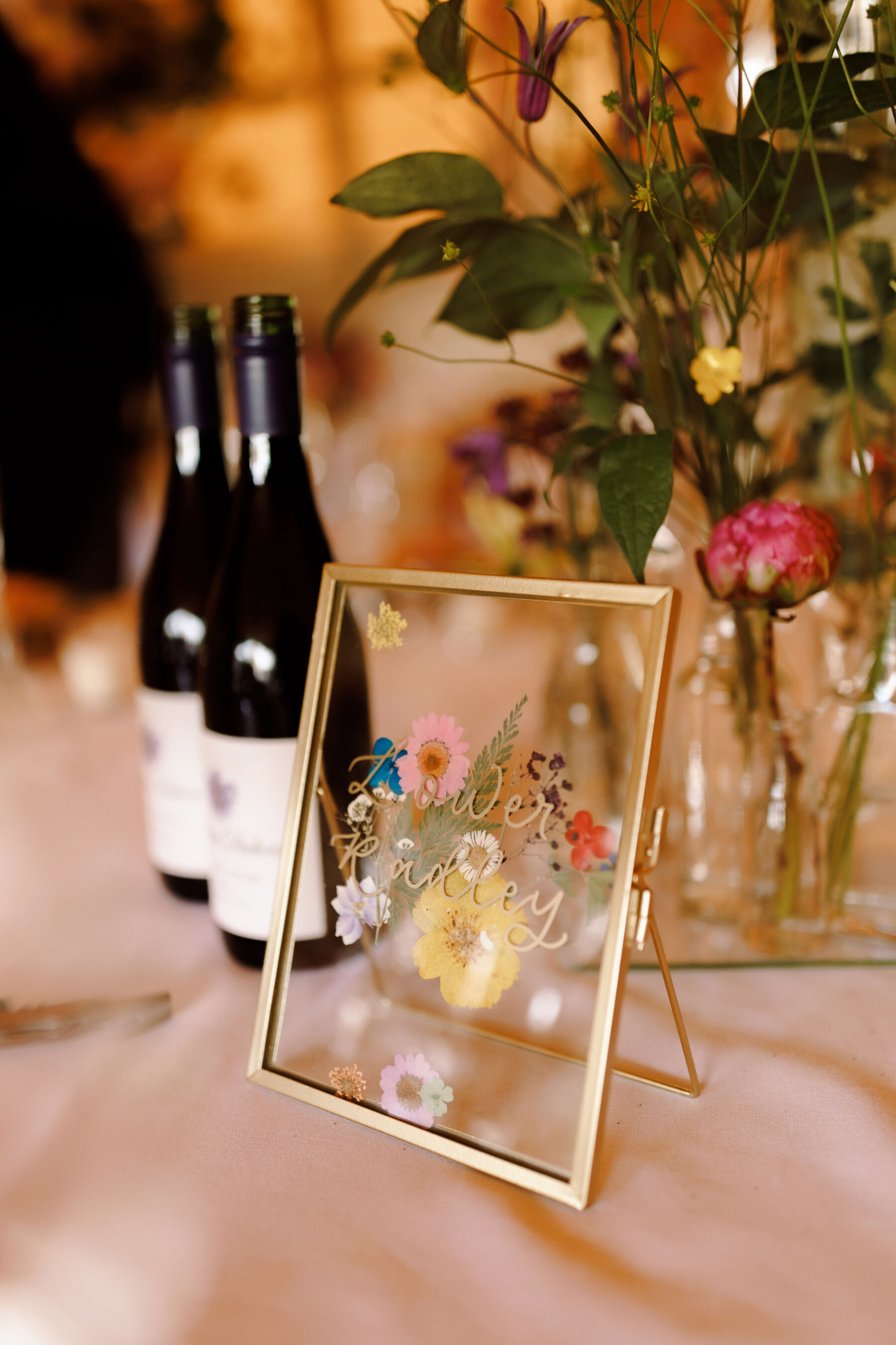 Wedding table name in a gold framed see through frame with pressed flowers. Midsummer Nights Dream inspired wedding.