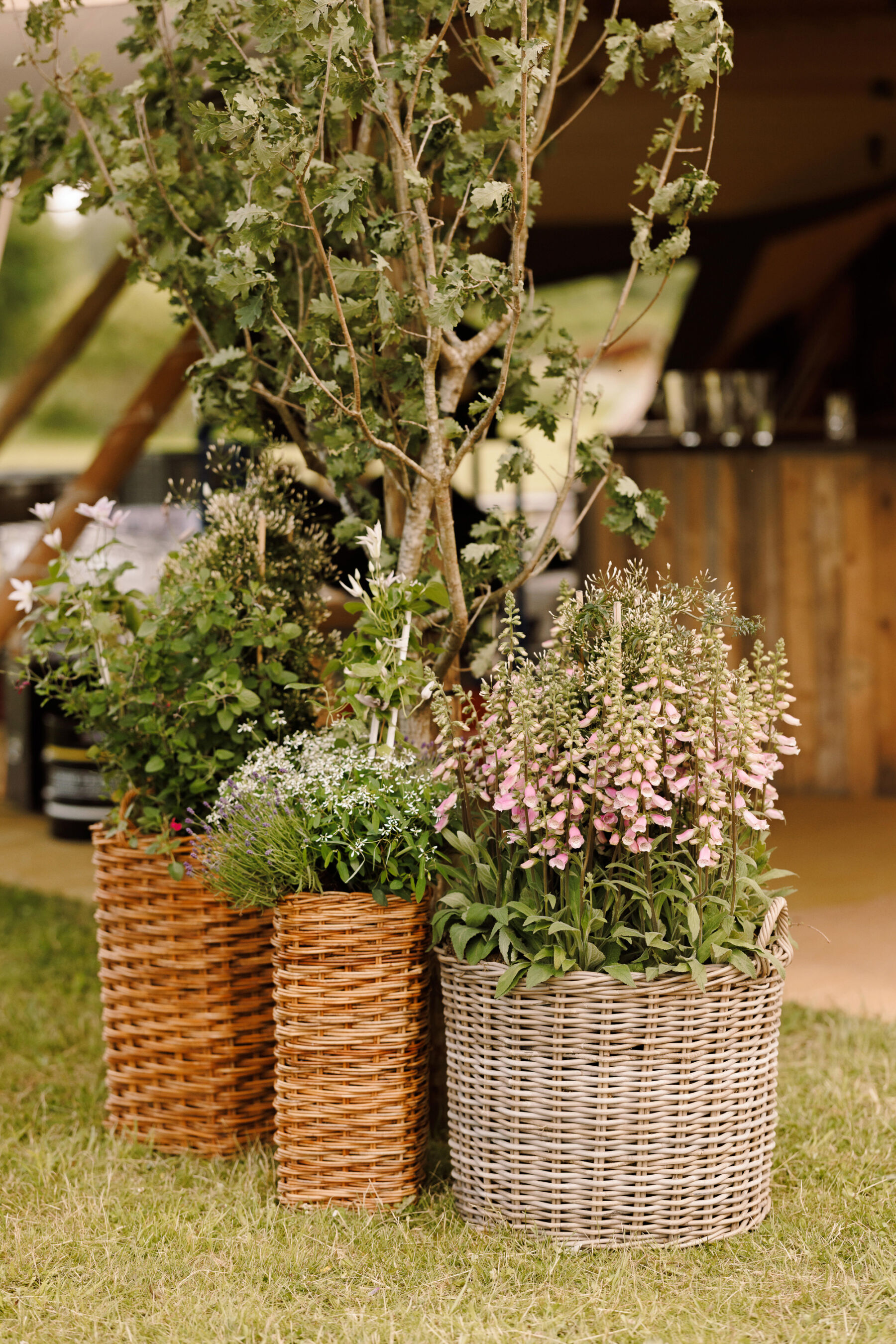 Whicker baskets filled with summer wedding flowers , to decorate a summer tipi wedding inspired by Midsummer Nights Dream.