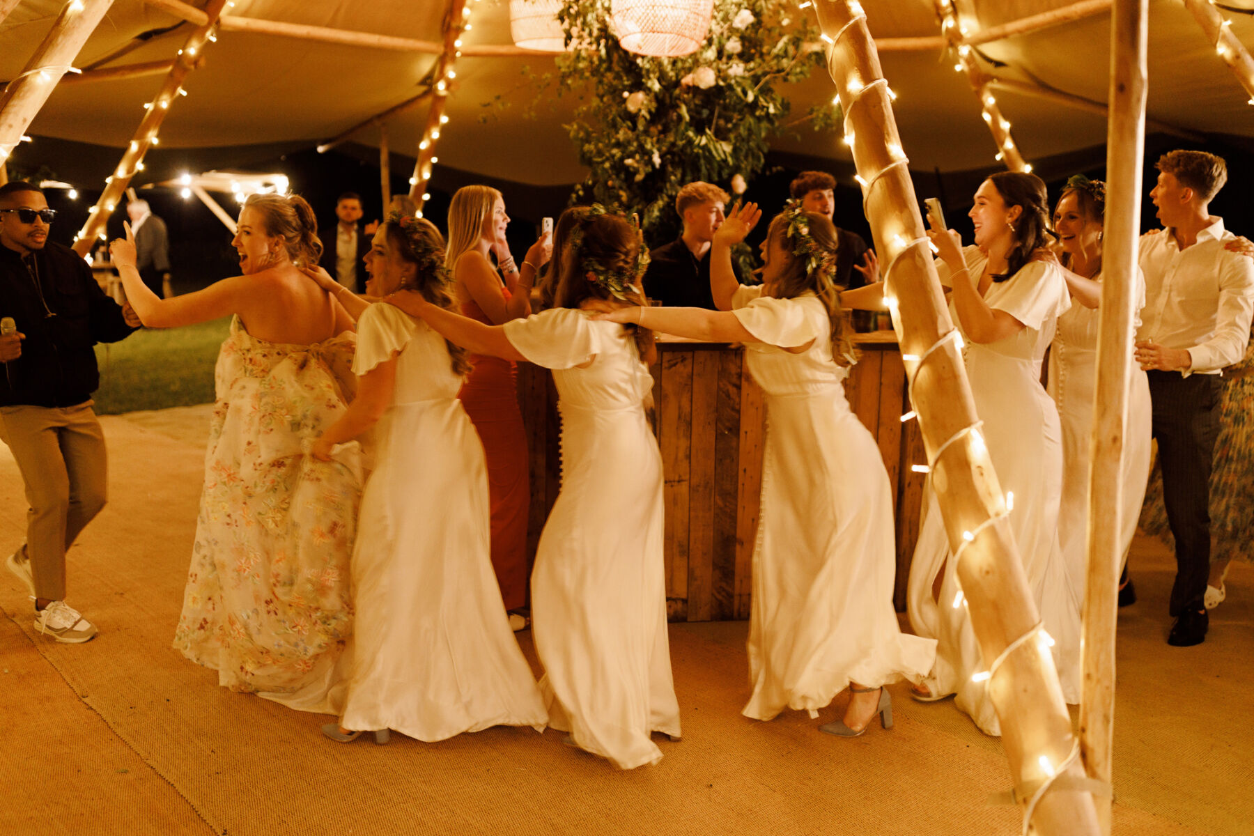Bridesmaid and the bride doing the conga inside the wedding tipi.