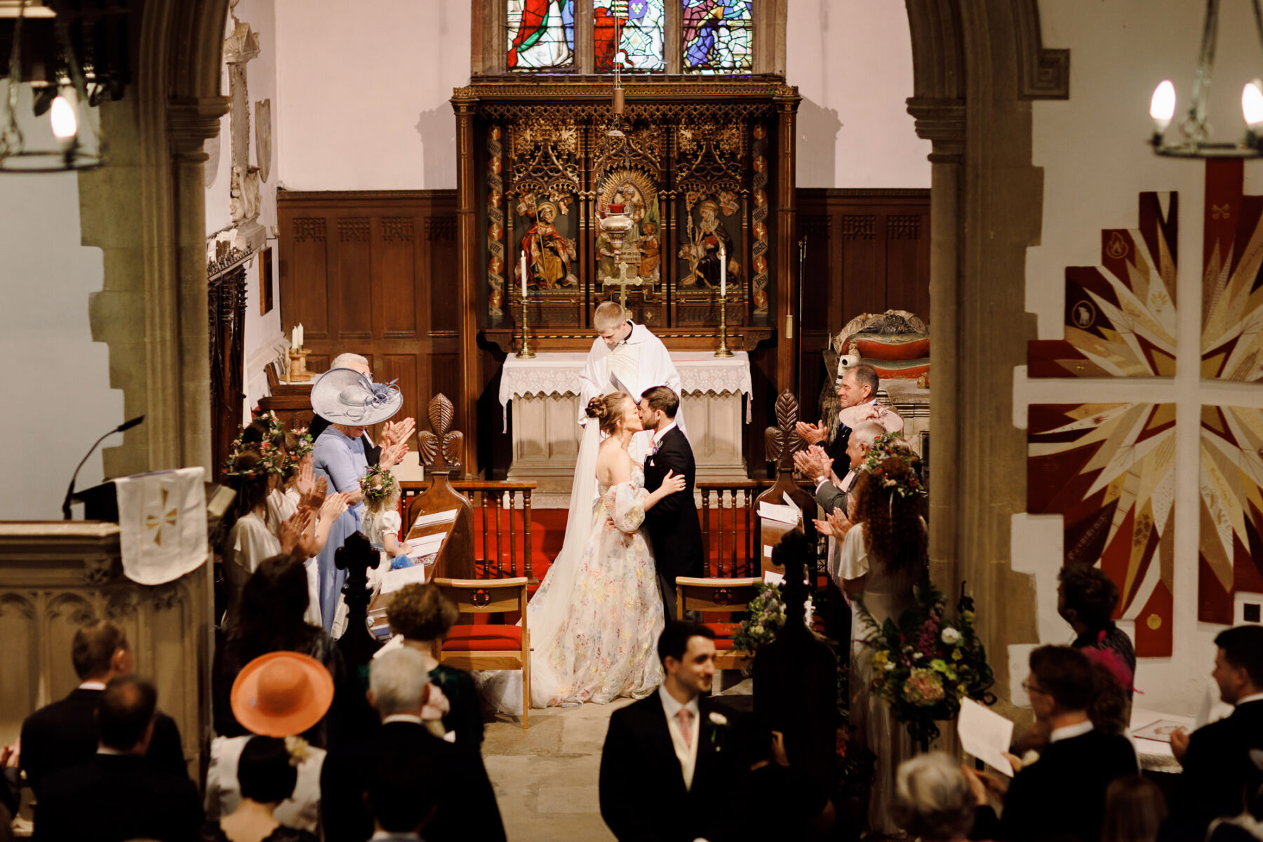 A Whimsical Tipi Wedding Inspired by A Midsummer Night's Dream with a House of Savin Floral Dress 21 Bride and groom standing at the alter in the church and kissing after their wedding ceremony.