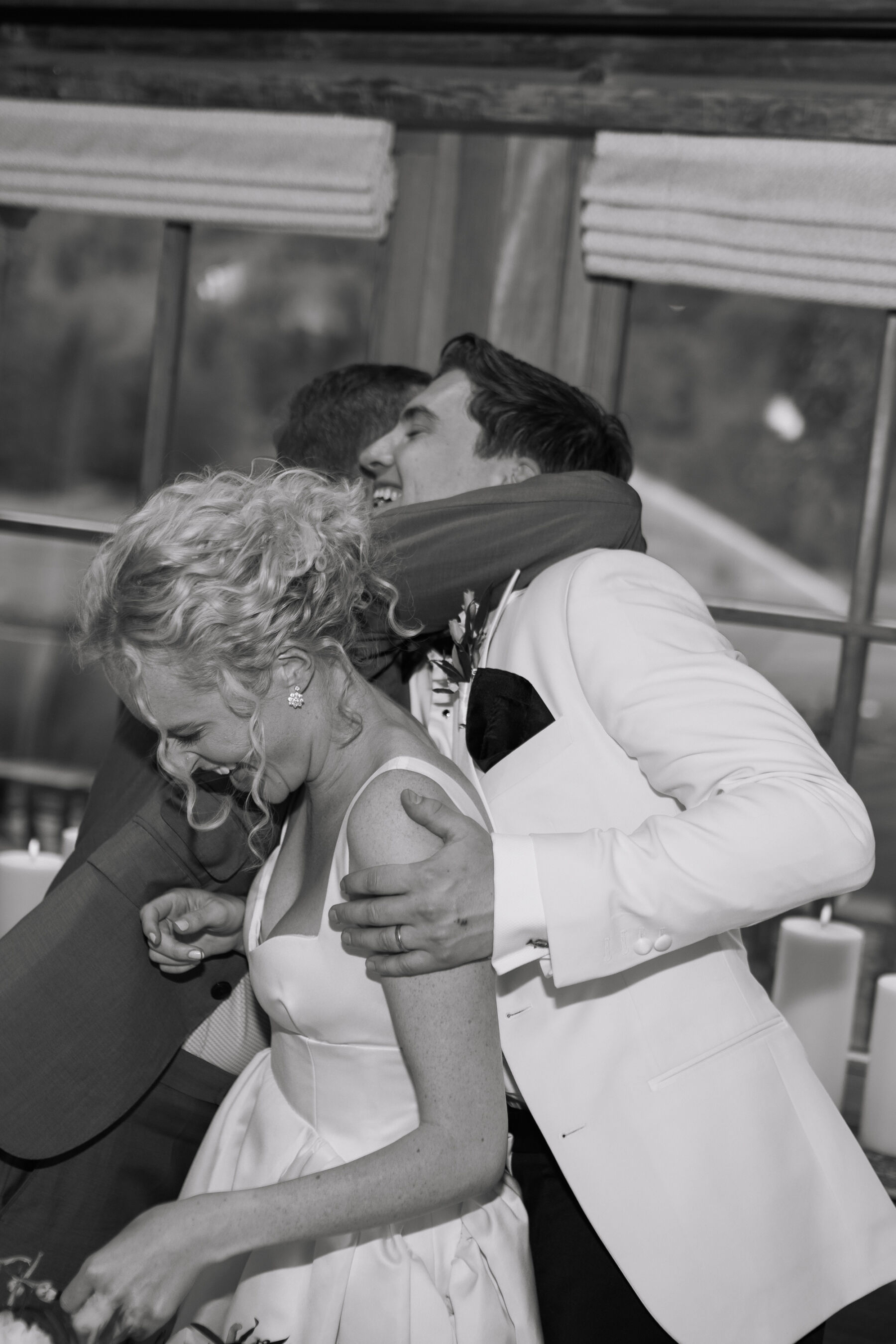 Georgia in Emilia Wickstead, For Her Classy & Elegant Black Tie Mountain Wedding in the Chamonix 41 Happy bride and groom laughing and joyful as they hug with guests. Emilia Wickstead wedding dress, groom in white tuedo.